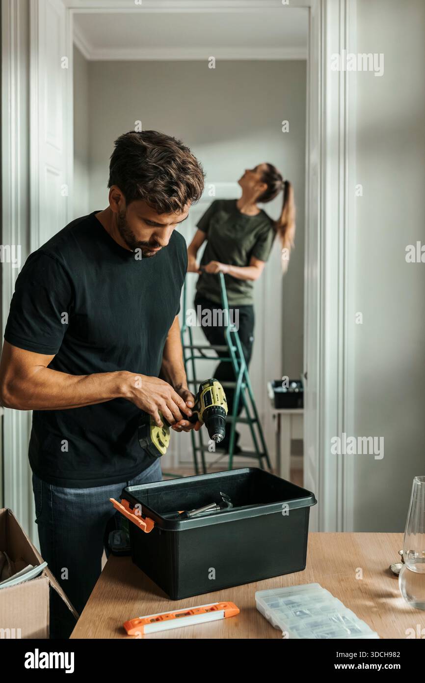 Uomo che regola la macchina perforatrice mentre apporta miglioramenti in una nuova casa Foto Stock