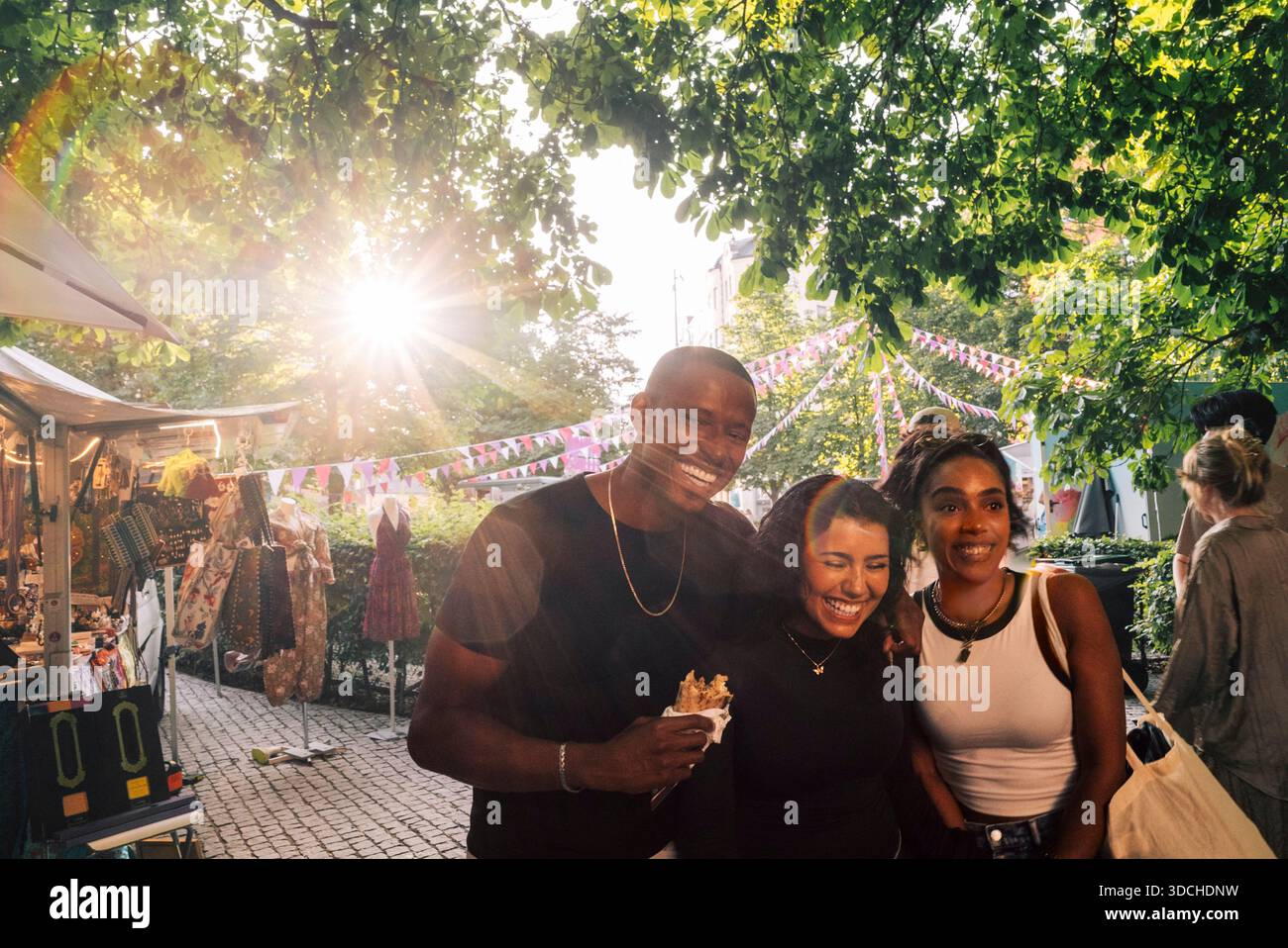 Il sole splende davanti agli amici multirazziali che posano per strada Foto Stock