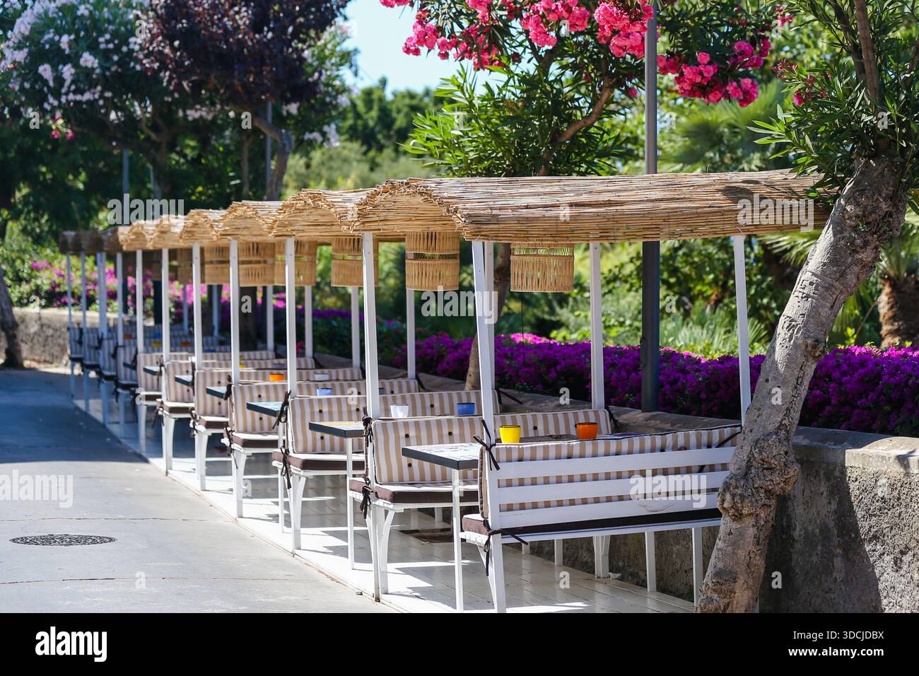 Intima alcova da pranzo all'aperto con un tavolo singolo che si affaccia sui giardini fioriti dell'isola di Capri. Foto Stock