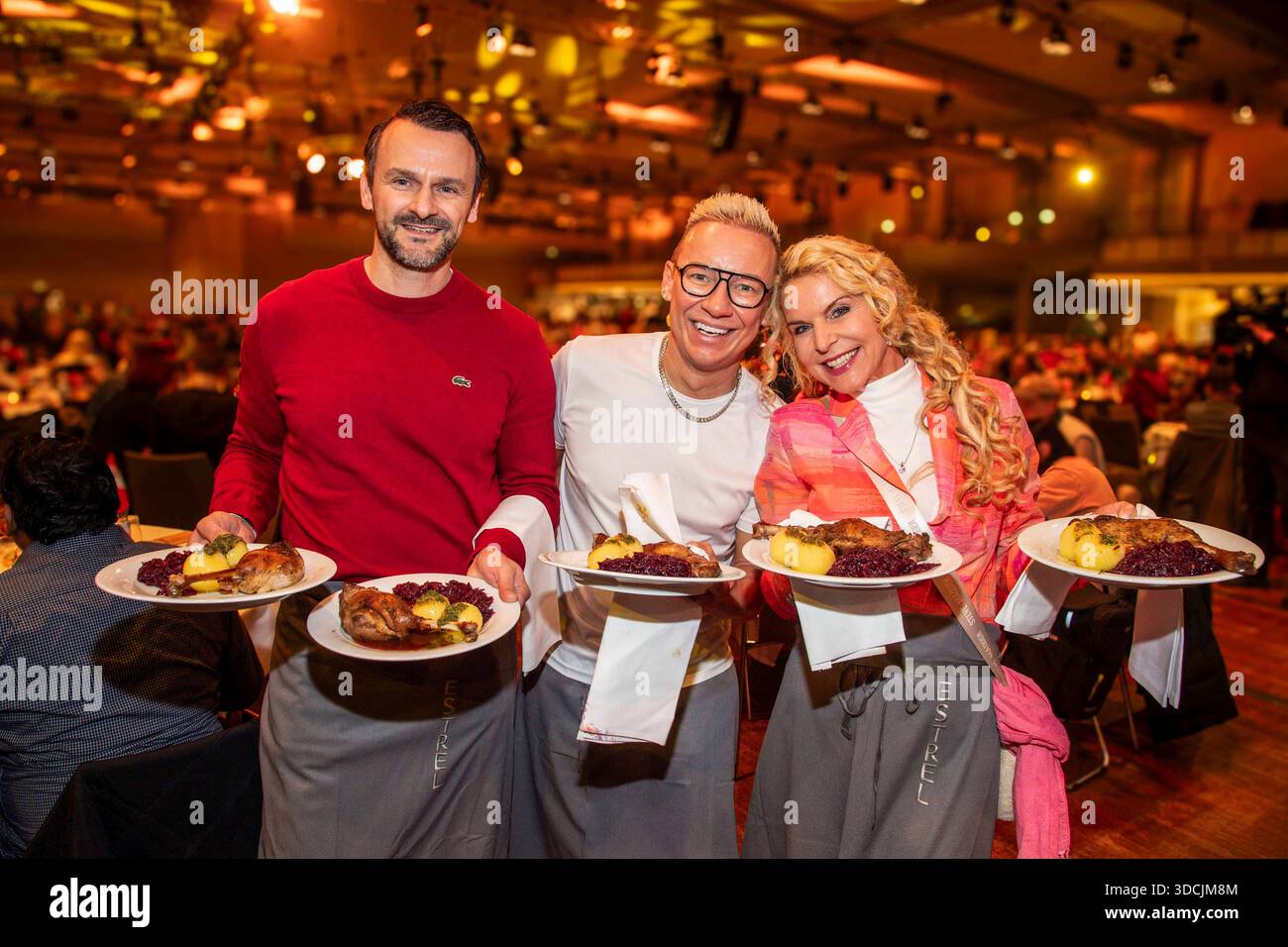 abb: David Biethig, Sascha Lauterbach und Victoria Herrmann als Promi Kellner beim Servieren von Teller mit Gaensekeuele Rotkohl und Kloesse bei der 31. Frank Zander Weihnachtsfeier Weihnachtsessen fuer Obdachlose und Beduerftige Menschen 2025 im Estrel Convention Center AM 22.12.2025 a Berlin Berlin Berlin Deutschland Foto Stock
