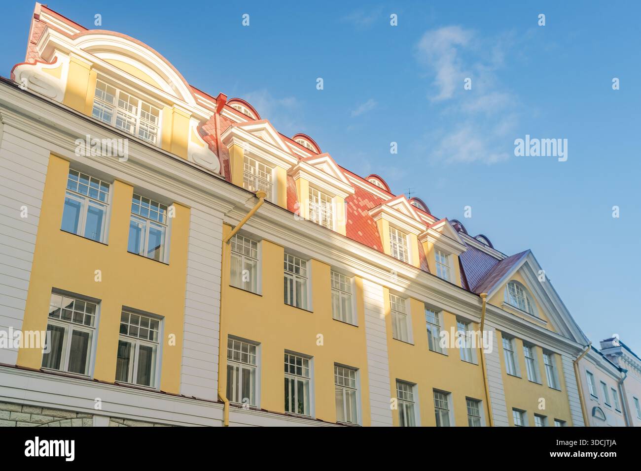 Vista di un edificio giallo con tegole rosse che contrasta con il cielo azzurro, creando una sorprendente armonia visiva, Tallinn, Contea di Harju, Estonia Foto Stock