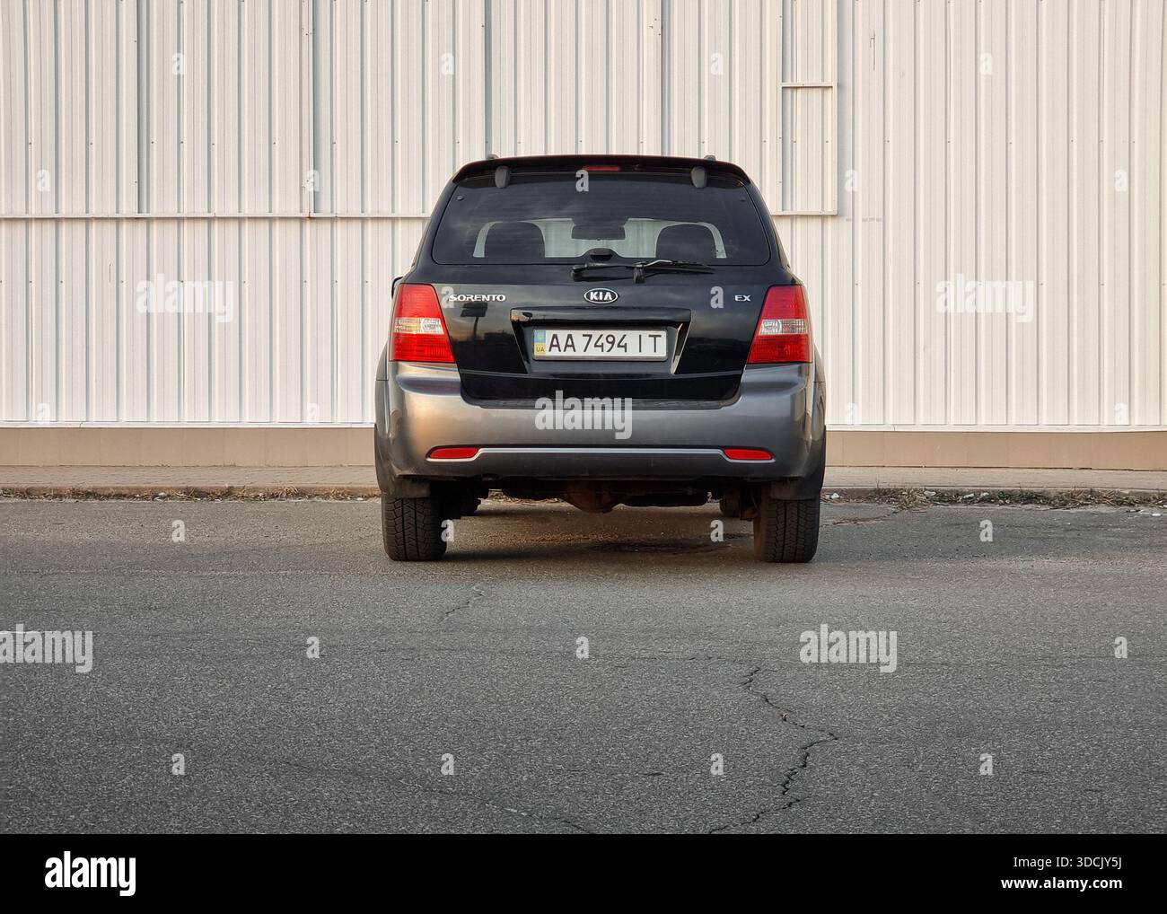Vista posteriore del SUV nero parcheggiato vicino a una parete bianca. Black KIA Sorento in una strada vicino ad alcuni edifici commerciali o industriali. Foto Stock