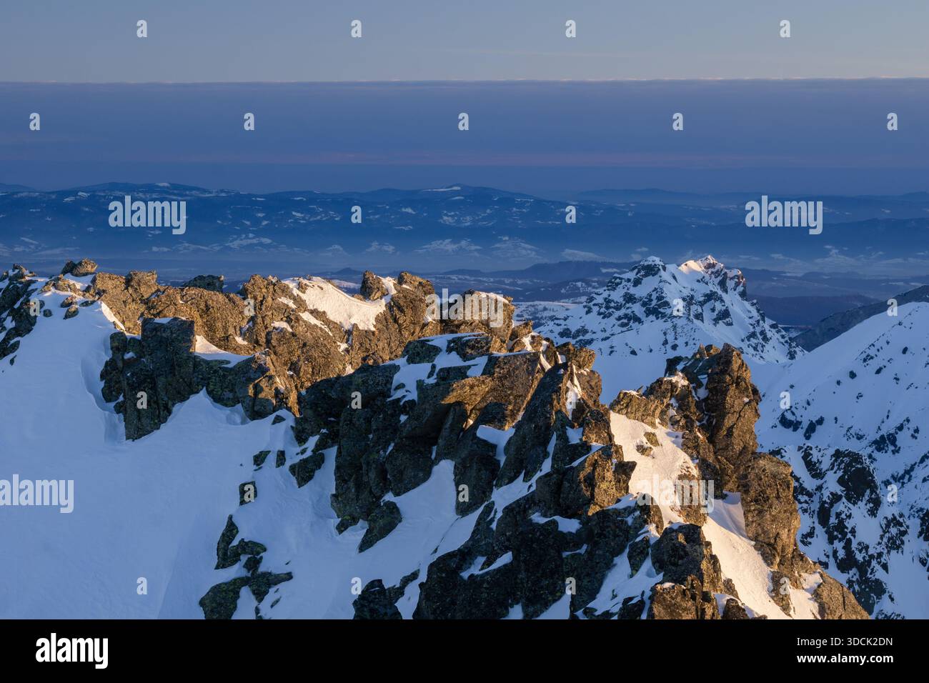 Vista aerea delle cime innevate che brillano con la luce del sole dorata che contrasta con l'orizzonte blu profondo, Koncista, regione di Presov, Slovacchia. Foto Stock
