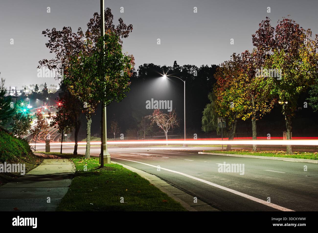 Lunga esposizione di percorsi leggeri per auto in una tranquilla strada suburbana di notte Foto Stock