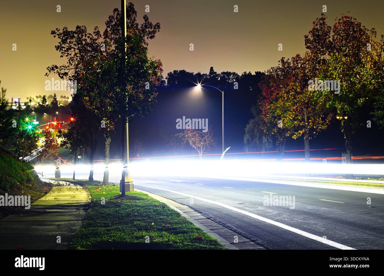 Percorsi luminosi a lunga esposizione su una tranquilla strada suburbana di notte Foto Stock