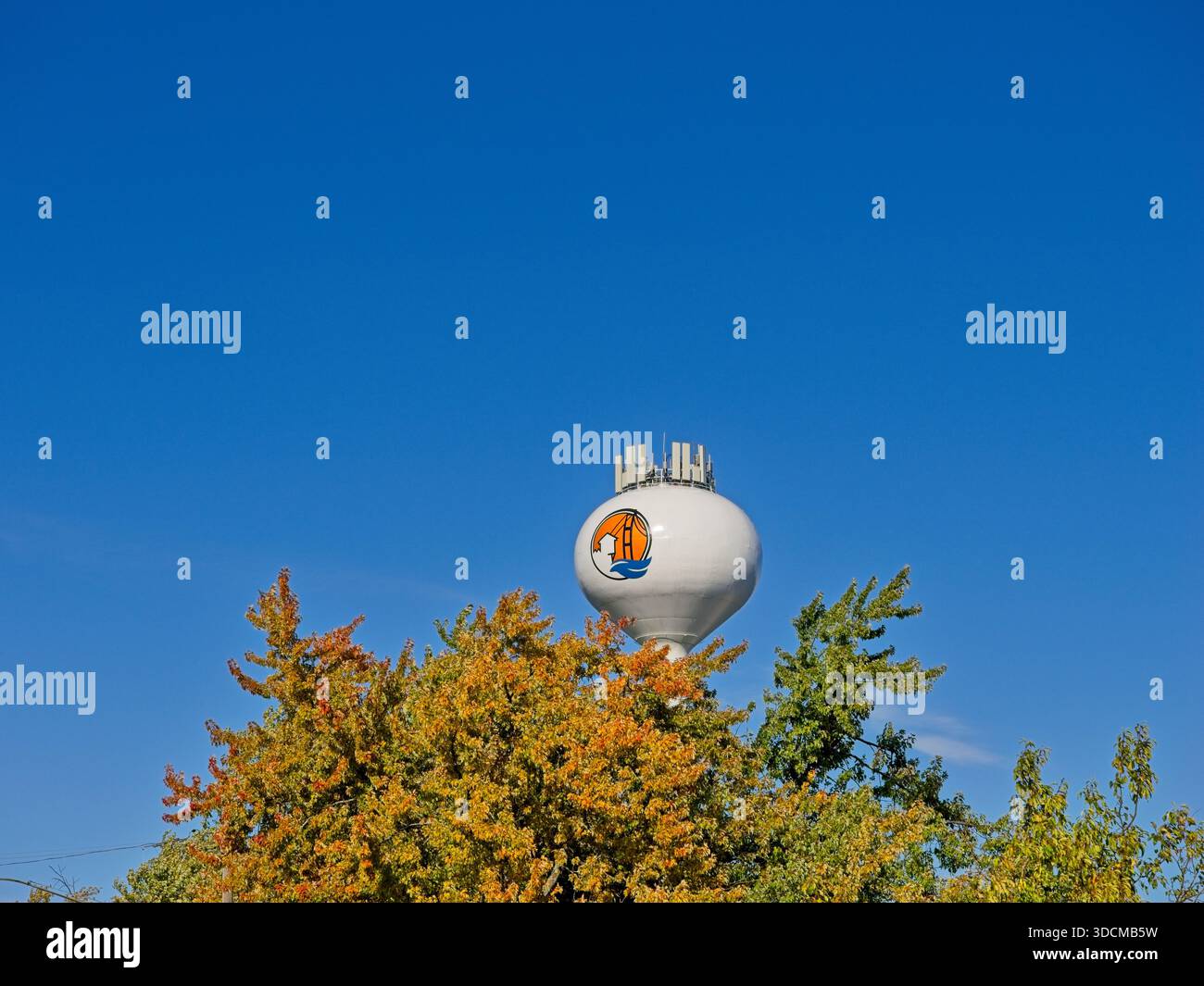 Logo del villaggio di Mackinaw City sulla torre sferoidale dell'acqua che si erge sopra gli alberi dai colori autunnali contro il cielo blu - Mackinaw City Michigan, ottobre 2025 Foto Stock