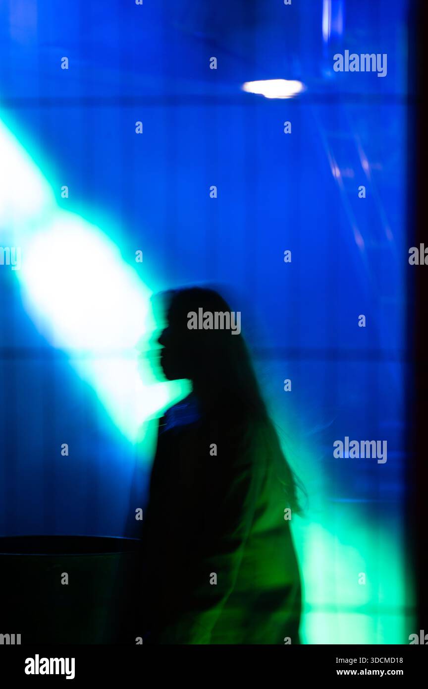 Sagoma spettrale di donna come personaggio che cammina con luce blu e verde Foto Stock