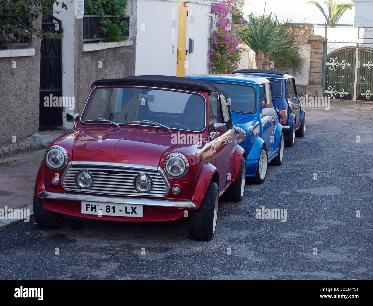Tre Mini classiche parcheggiate su una strada a Tangeri, una rossa e due blu di sfumature diverse. Marocco. Dic 2025 Foto Stock