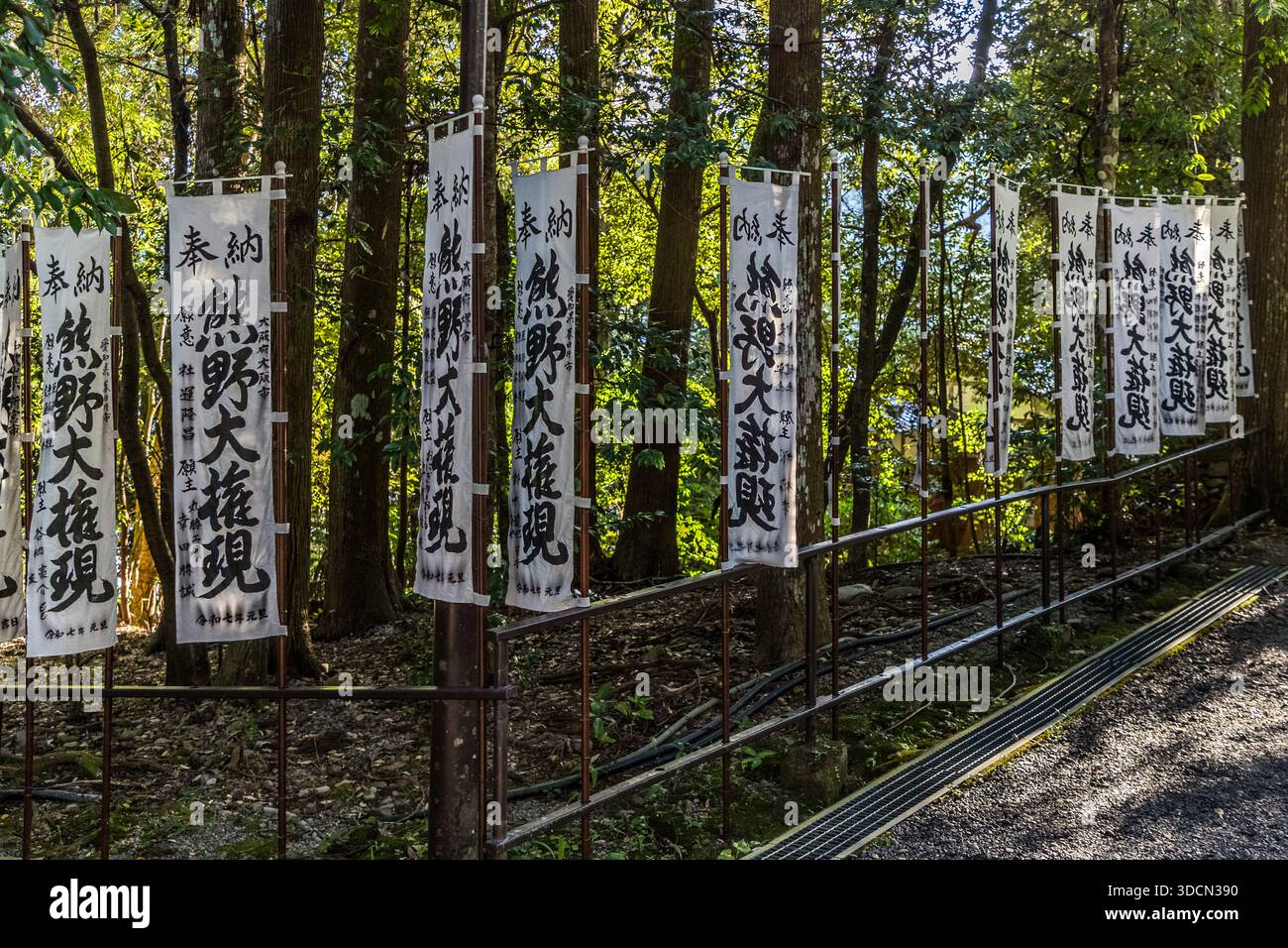 Le bandiere del tempio, le bandiere bianche con calligrafia nera, sono goshuin o bandiere del tempio (nōrei o shinsatsu) che recano i nomi dei donatori, preghiere o dedica al kami, simboleggiando la protezione e il sostegno spirituale per la comunità. Bandiere bianche con scritta giapponese appendono su una recinzione a Kumano Hongu Taisha vicino a Tanabe. Prefettura di Wakayama, Giappone Foto Stock
