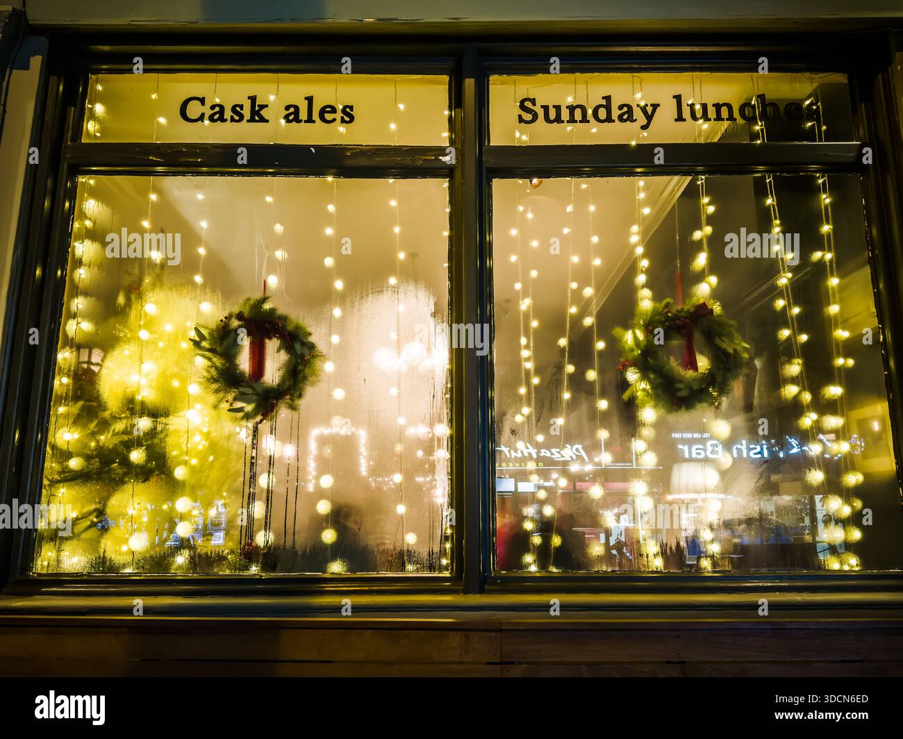 Londra, Inghilterra – tradizionale finestra da pub decorata con luci e ghirlande natalizie, decorazioni per l'ospitalità festosa Foto Stock