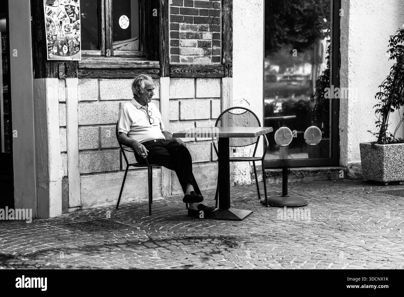 Uomo anziano seduto a un piccolo tavolo all'aperto a Como, Lombardia, Italia. Foto Stock