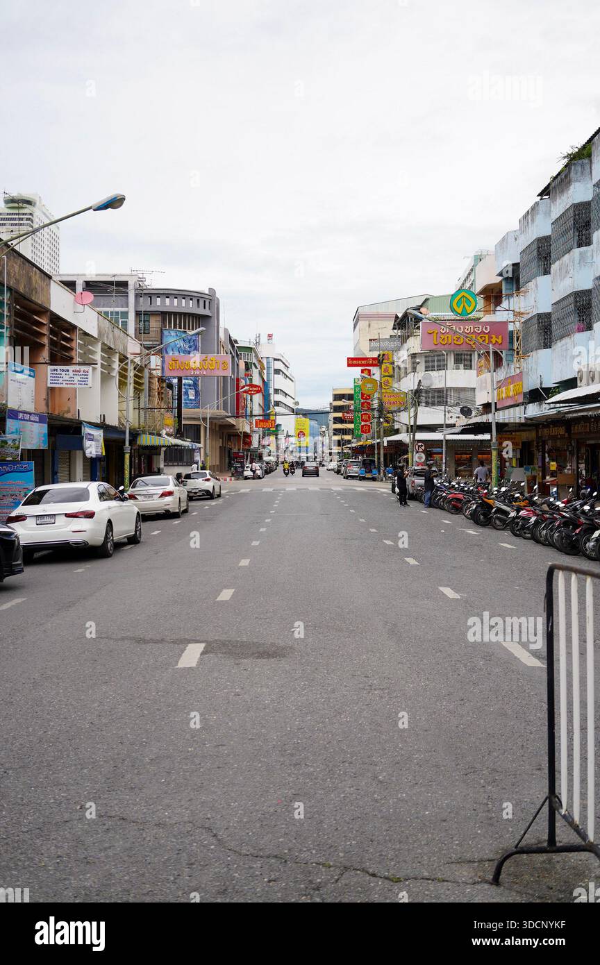 Hat Yai, Thailandia - 18 ottobre 2024 - strada stretta a Hat Yai, Thailandia, con auto, motociclette, insegne tailandesi, e tradizionale magazzino urbano Foto Stock
