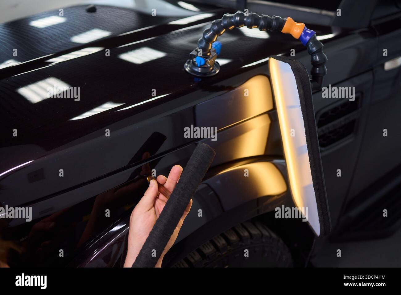 Un tecnico esperto utilizza con competenza attrezzature specializzate dedicate alla rimozione e alla riparazione delle ammaccature delle auto Foto Stock