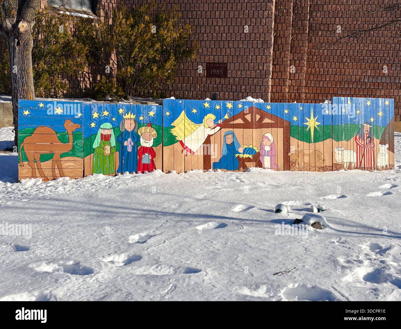 Presepe natalizio all'aperto. Decorazioni religiose, opere d'arte per le feste. Di fronte a una chiesa in un giorno d'inverno innevato. Foto Stock