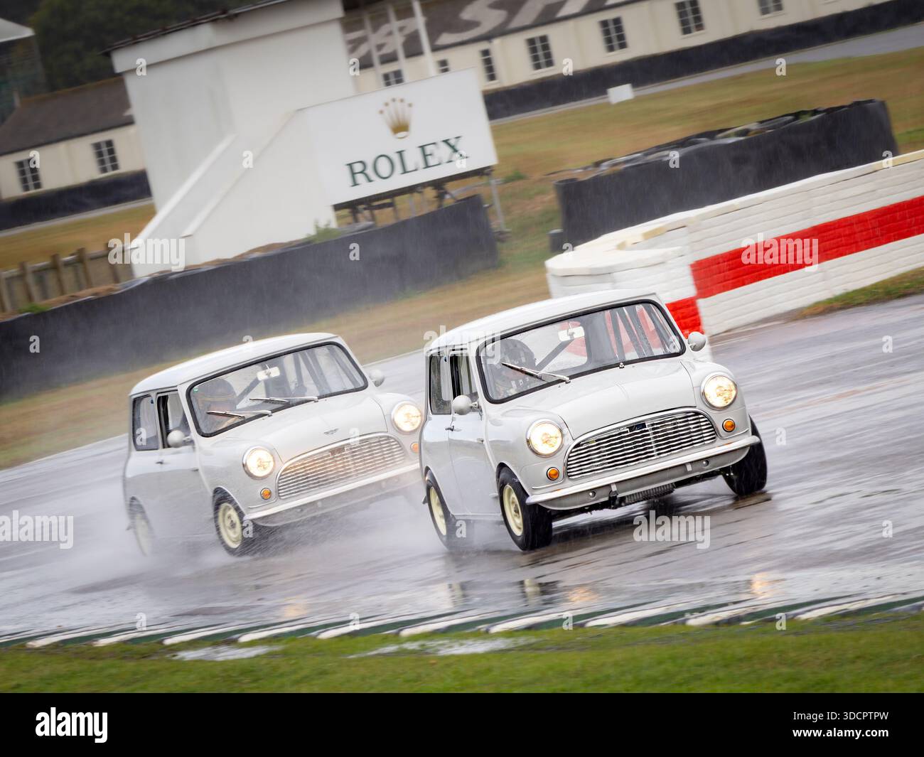Due mini auto classiche di colore grigio che guidano sul bagnato al Goodwood Revival 2025 Foto Stock