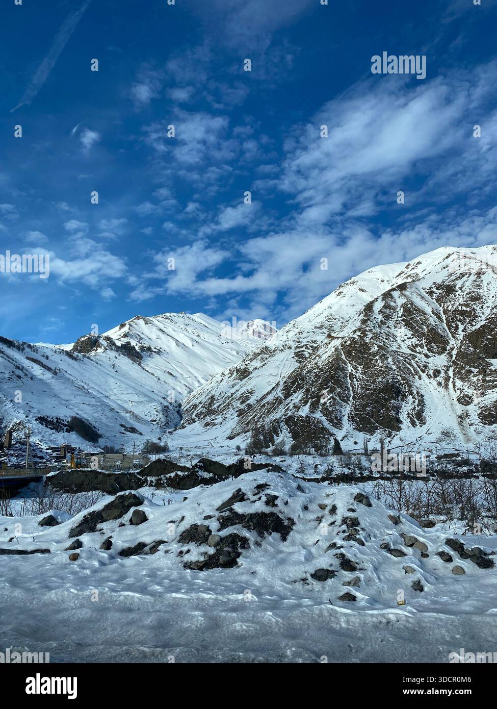 Paesaggio di montagna innevato sotto il cielo azzurro, perfetto per le scene e i progetti invernali. Foto mobile Foto Stock