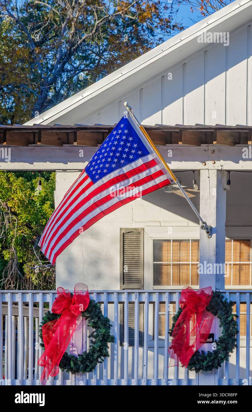 Ghirlande di Natale e una bandiera americana decorano un portico anteriore, il 13 dicembre 2025, a Dauphin Island, Alabama. Foto Stock