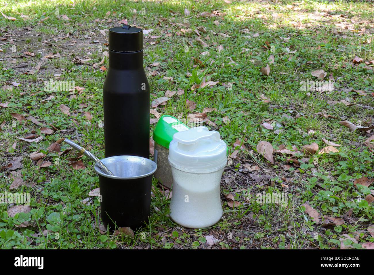 Kit completo MATE con thermos nero, cannuccia, contenitore yerba e vaschetta per lo zucchero sull'erba. Infusione tradizionale per campeggio e gite nella natura. Foto Stock