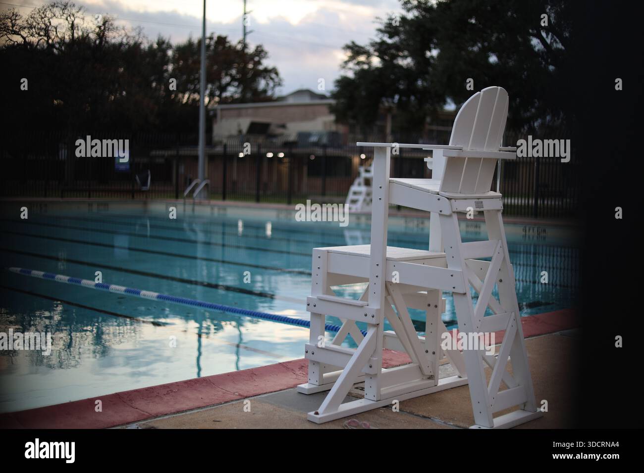 Poltrona bagnino di fronte alla piscina vuota Foto Stock