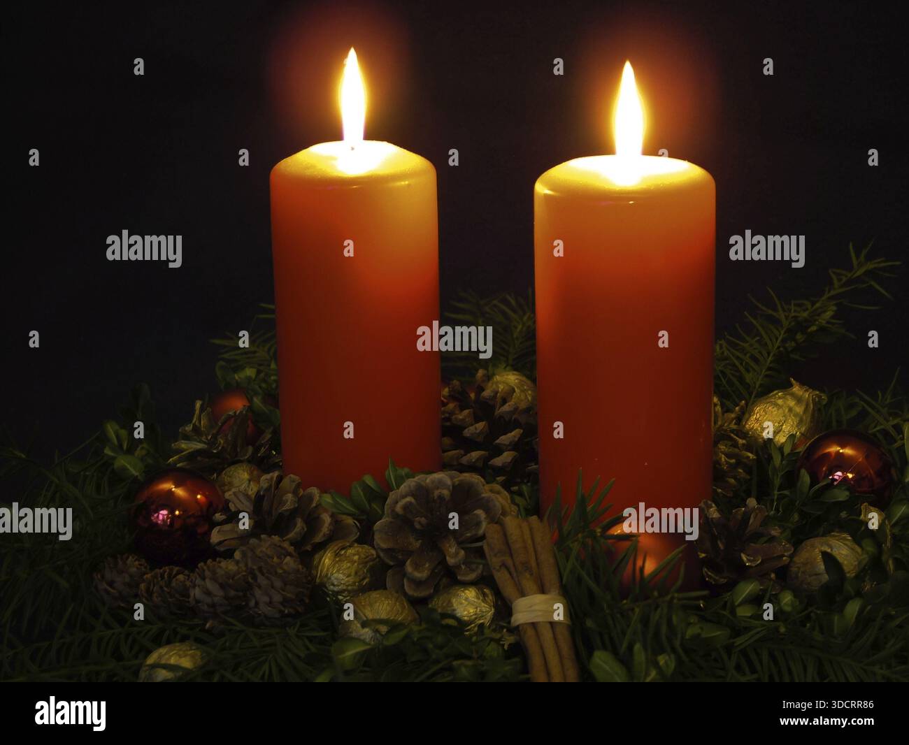 Corona d'avvento festiva con due candele accese, coni di pino, coni di pino, rami di pino, bastoncini di cannella, palle di Natale e noci dorate, noci, Chri Foto Stock