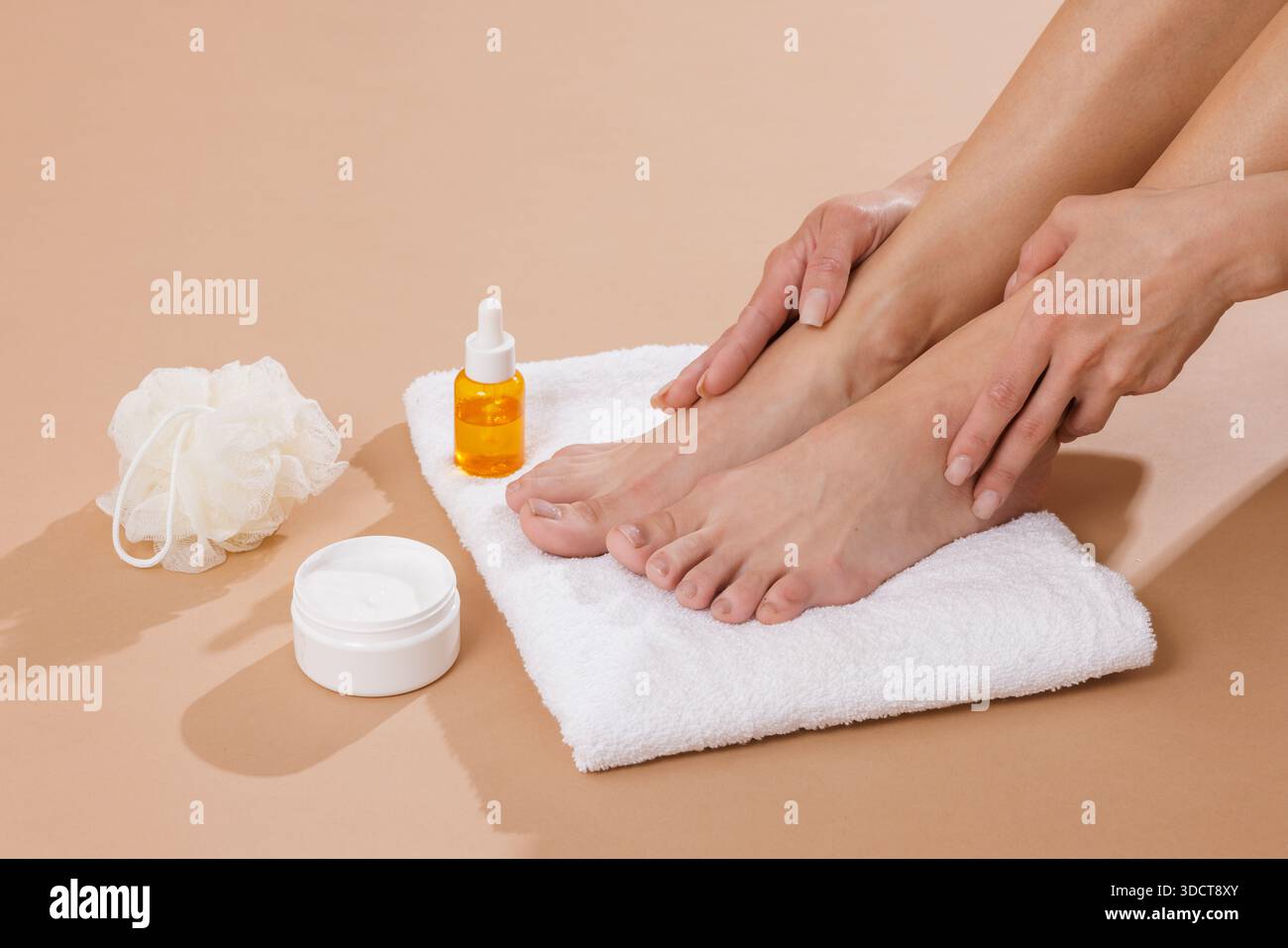 Primo piano di una donna che idrata i piedi con olio per la cura della pelle e crema su asciugamano per il relax del benessere e la pelle morbida e liscia Foto Stock
