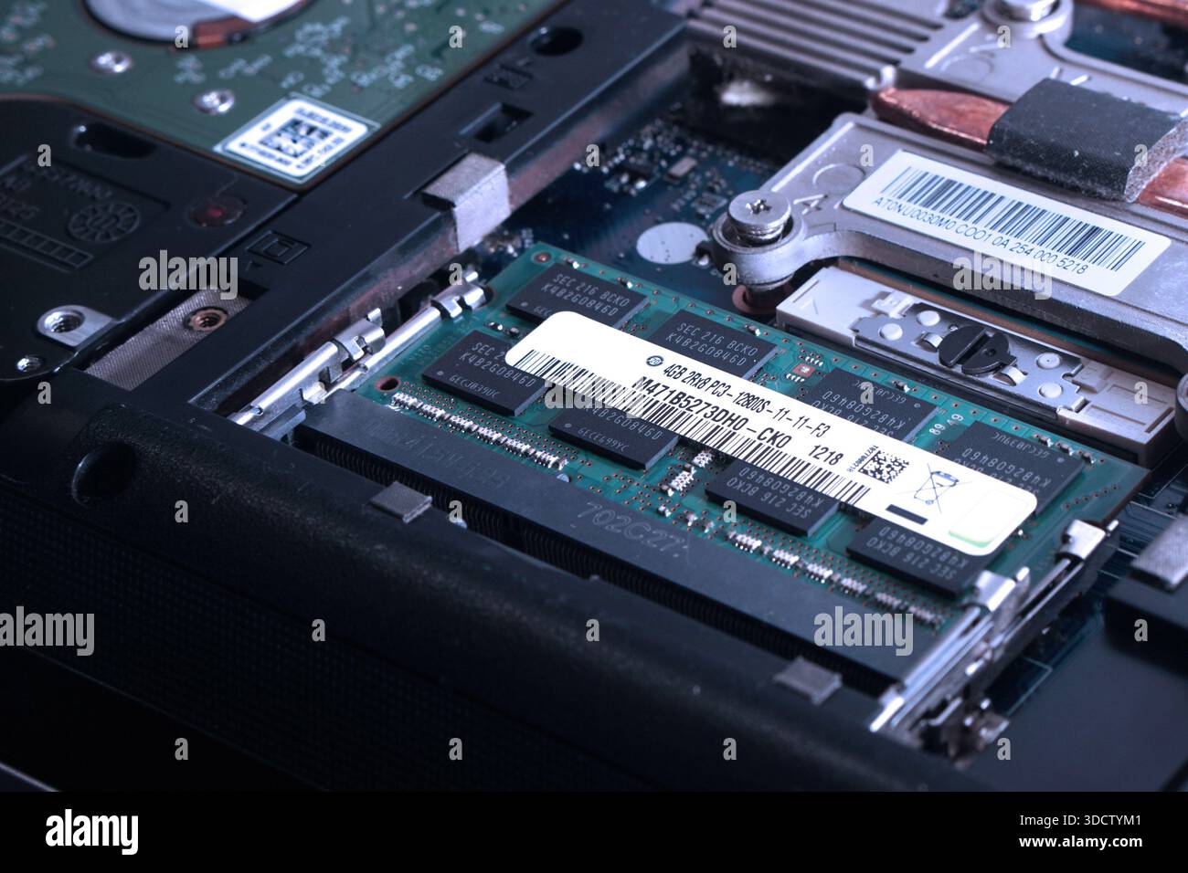 Immagine dettagliata di un modulo di memoria inserito saldamente nello slot SODIMM di una scheda madre per laptop. Concentrarsi sull'etichetta delle specifiche, sui codici a barre e sulla clip Foto Stock
