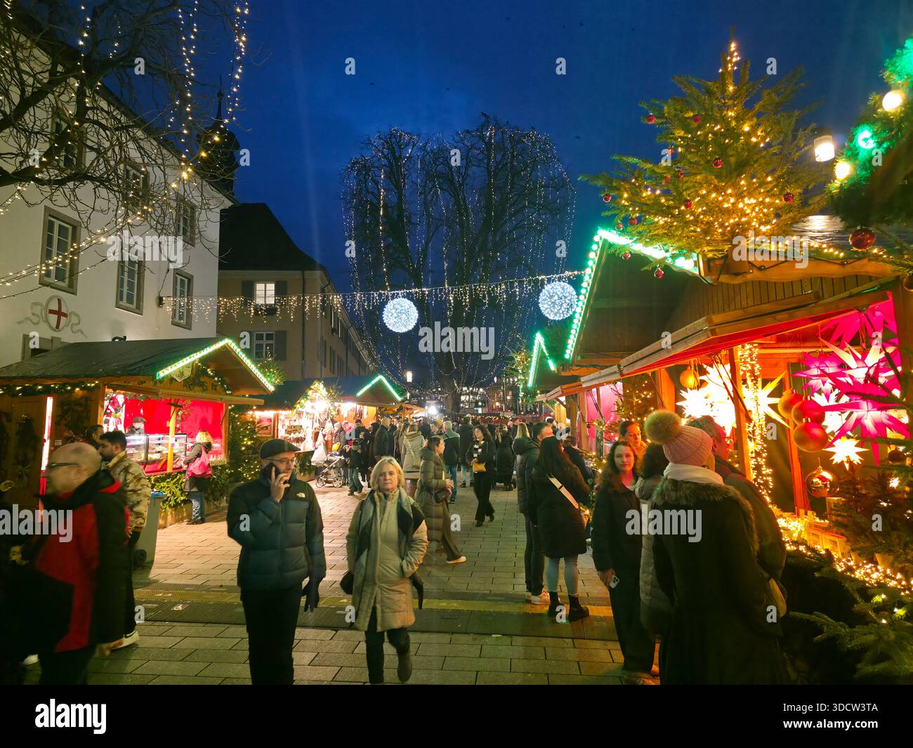 Freiburg im Breisgau, Germania, 19 dicembre 2025, famoso mercatino di Natale nella città vecchia vivace atmosfera Blue Hour Foto Stock