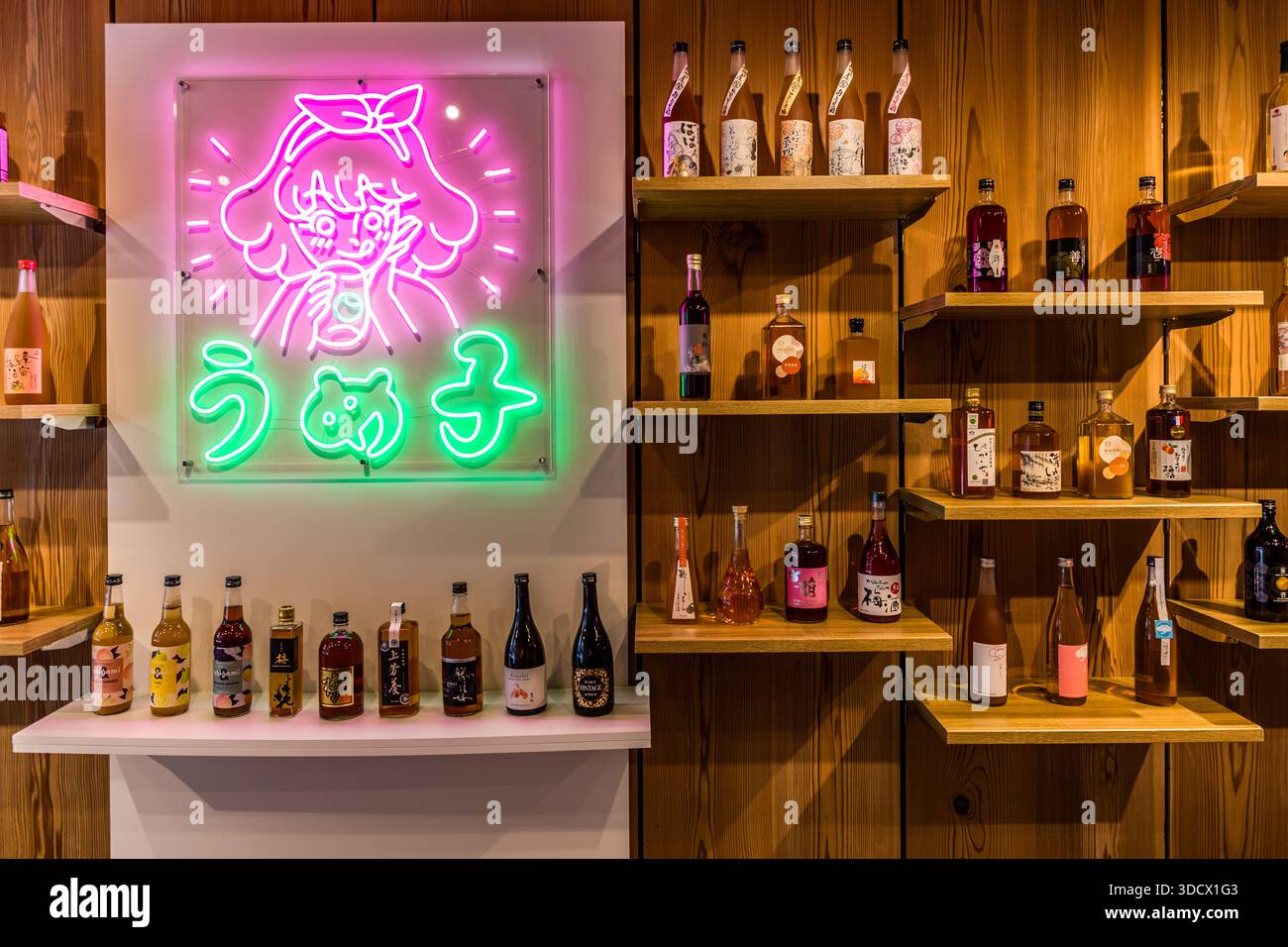 Uno scaffale di legno nel bar Umeshu di Tanabe contiene dozzine di bottiglie di liquore alla prugna giapponese, umeshu. La prefettura di Wakayama fornisce più del 60% del raccolto giapponese di ume, circa 40.000 tonnellate all’anno, principalmente la varietà Nanko-ume. La regione di Tanabe/Minabe produce umeshu da circa 400 anni; all’inizio del XVII secolo, il signore feudale Naotsugu Ando esentò i frutteti di prugne dalle tasse. L’umeshu ha un sapore dolce e aspro con note fruttate di frutta a nocciolo e mandorla; una prugna si trova spesso sul fondo della bottiglia. Foto Stock