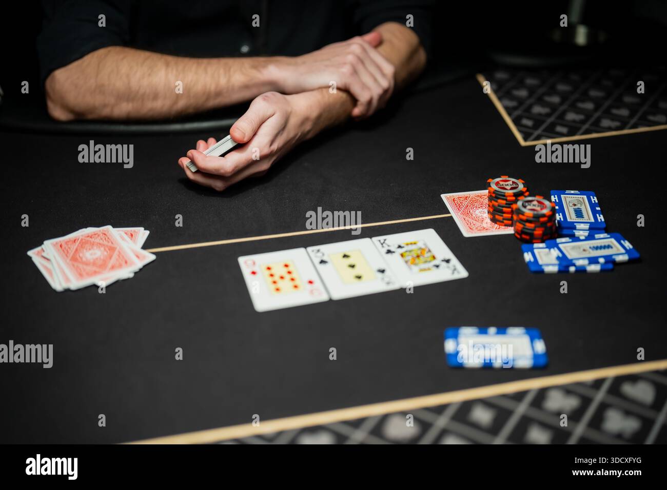 Gioco di poker da casinò professionale in corso con carte community visibili, controllo del dealer e azioni di scommessa dei giocatori su un tavolo da gioco regolamentato Foto Stock