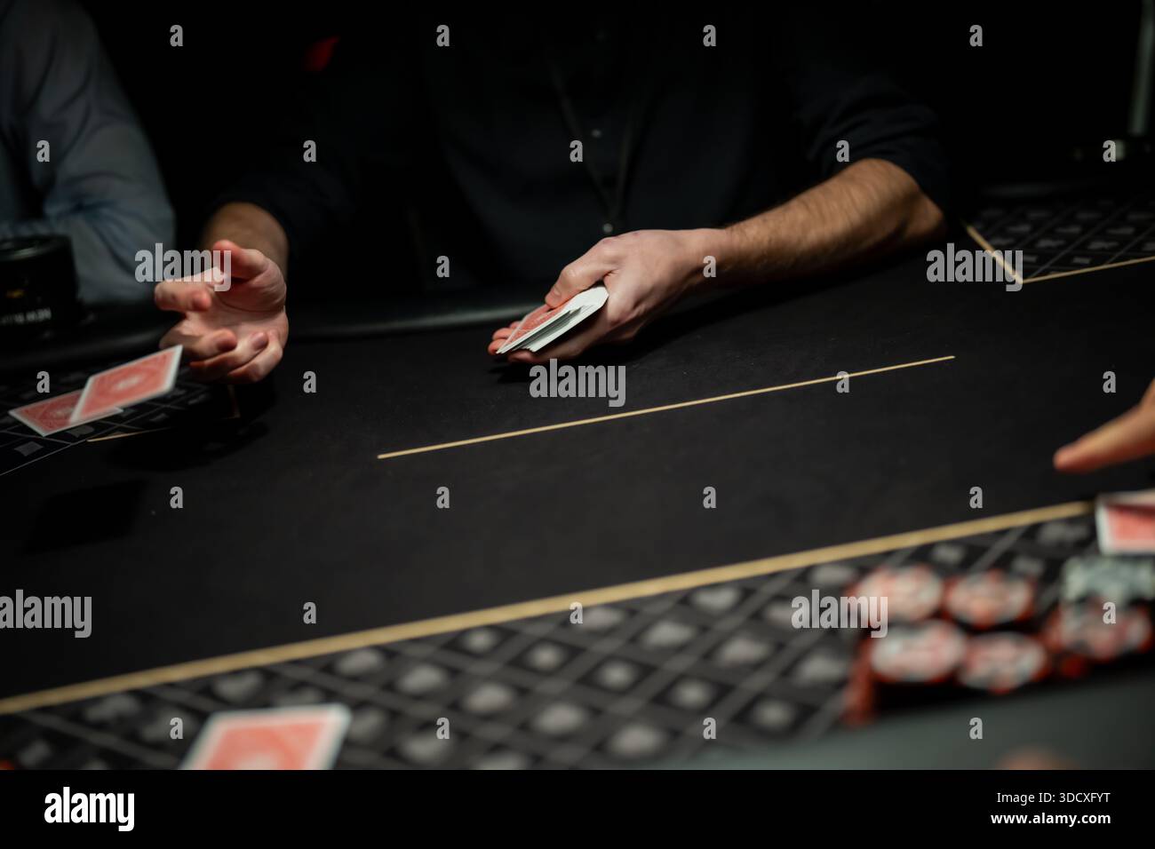Azione dal vivo del tavolo da poker che mostra la mano del mazziere che sfreccia la carta da gioco sulla superficie in feltro mentre i giocatori aspettano, illustrando il mec del casinò professionale Foto Stock