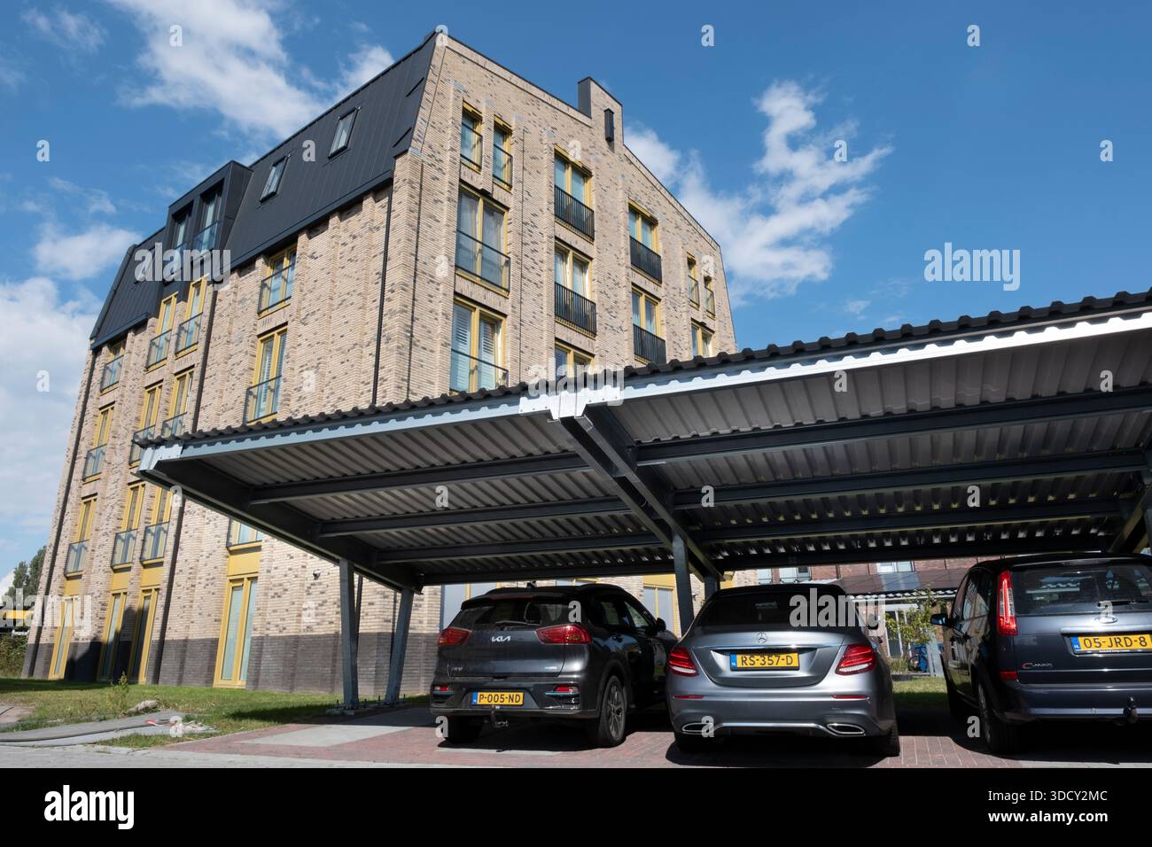 Le auto sono parcheggiate sotto una tettoia con pannelli solari in un nuovo condominio. Energia sostenibile e ombra allo stesso tempo Foto Stock