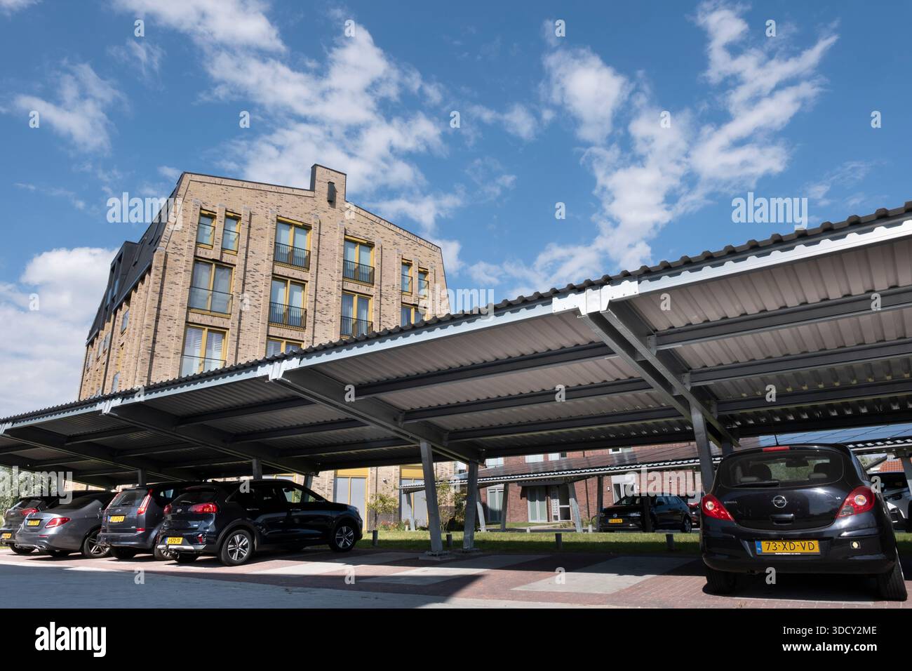 Le auto sono parcheggiate sotto una tettoia con pannelli solari in un nuovo condominio. Energia sostenibile e ombra allo stesso tempo Foto Stock