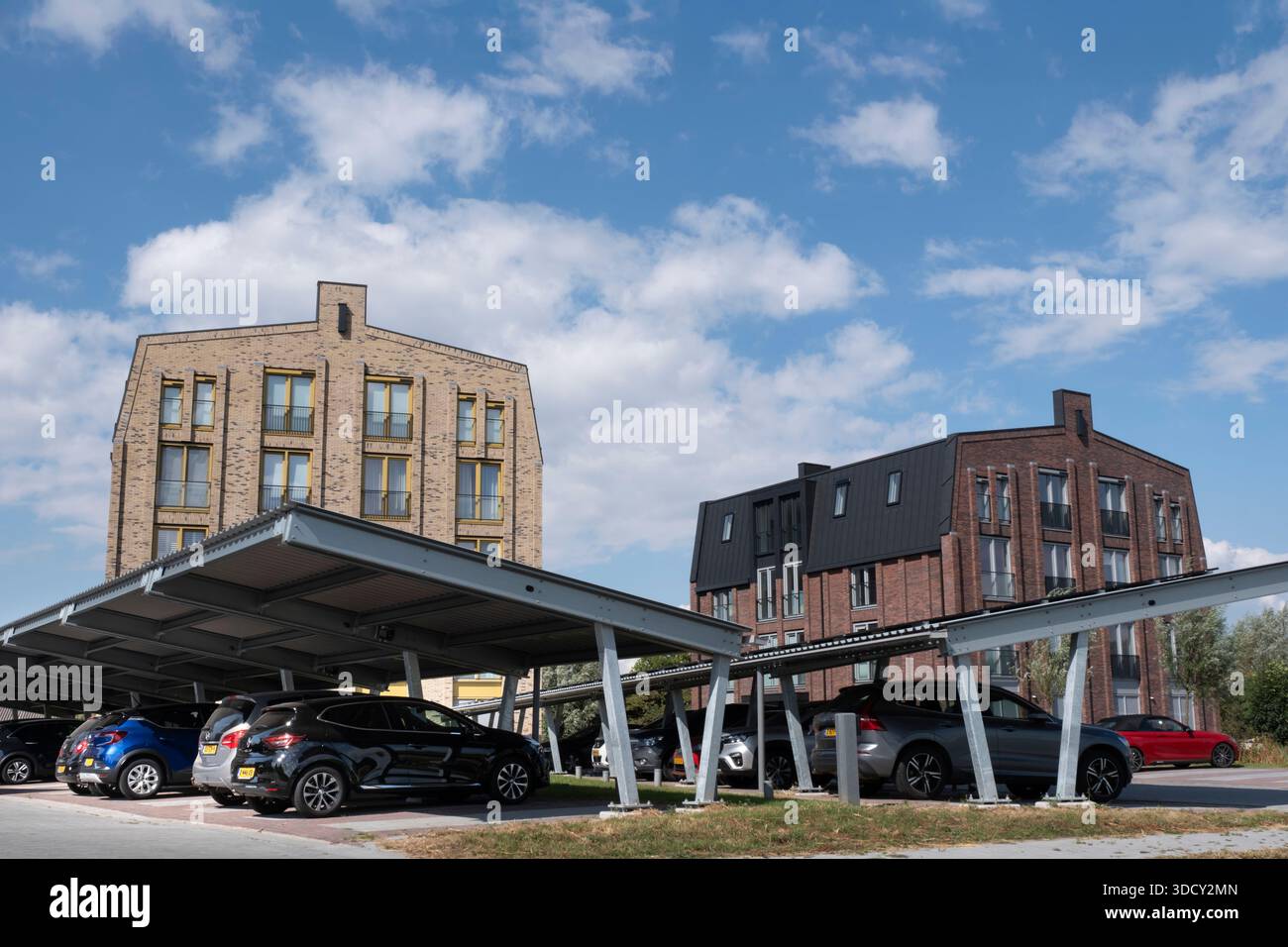 Le auto sono parcheggiate sotto una tettoia con pannelli solari in un nuovo condominio. Energia sostenibile e ombra allo stesso tempo Foto Stock