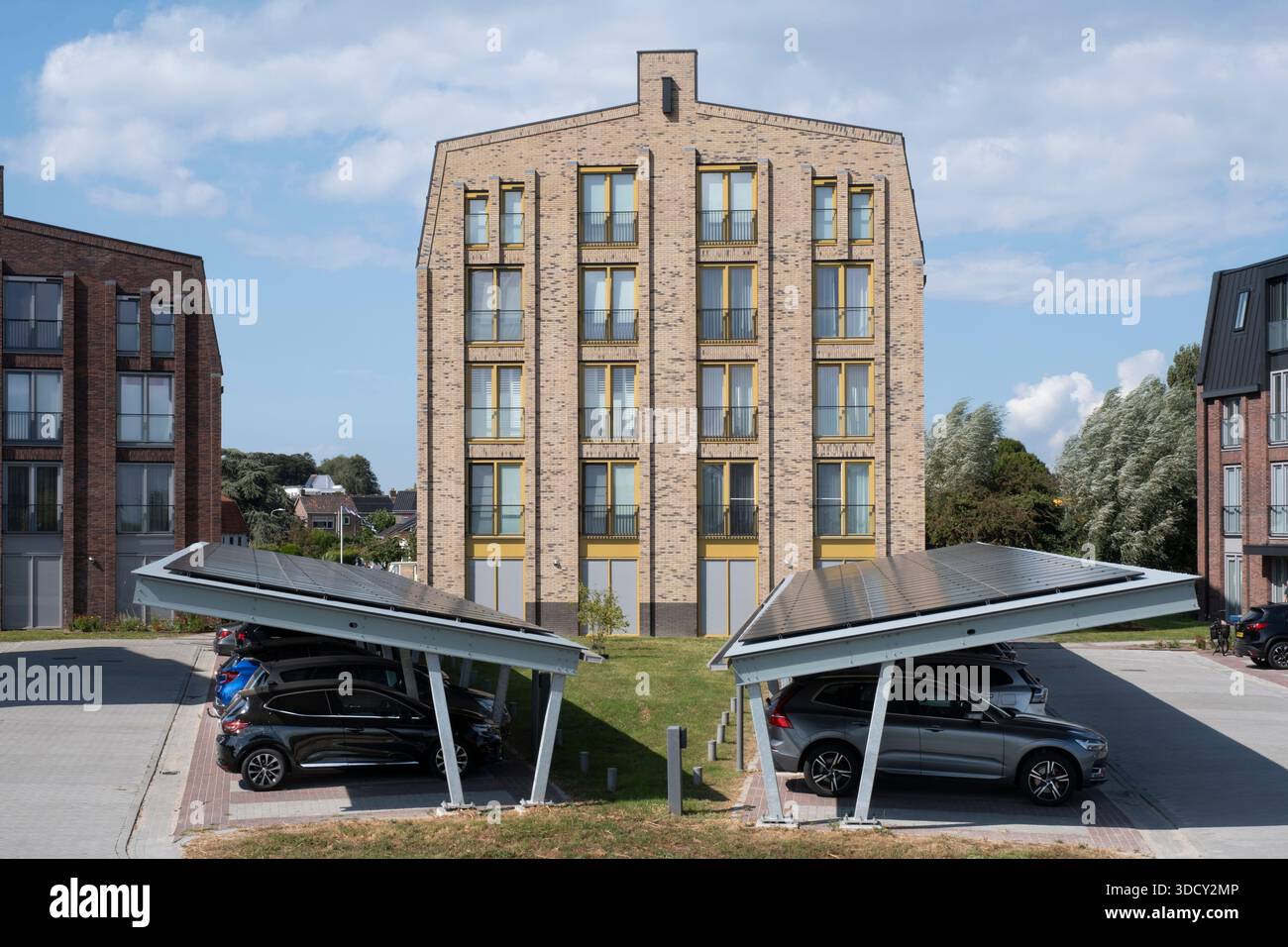 Le auto sono parcheggiate sotto una tettoia con pannelli solari in un nuovo condominio. Energia sostenibile e ombra allo stesso tempo Foto Stock