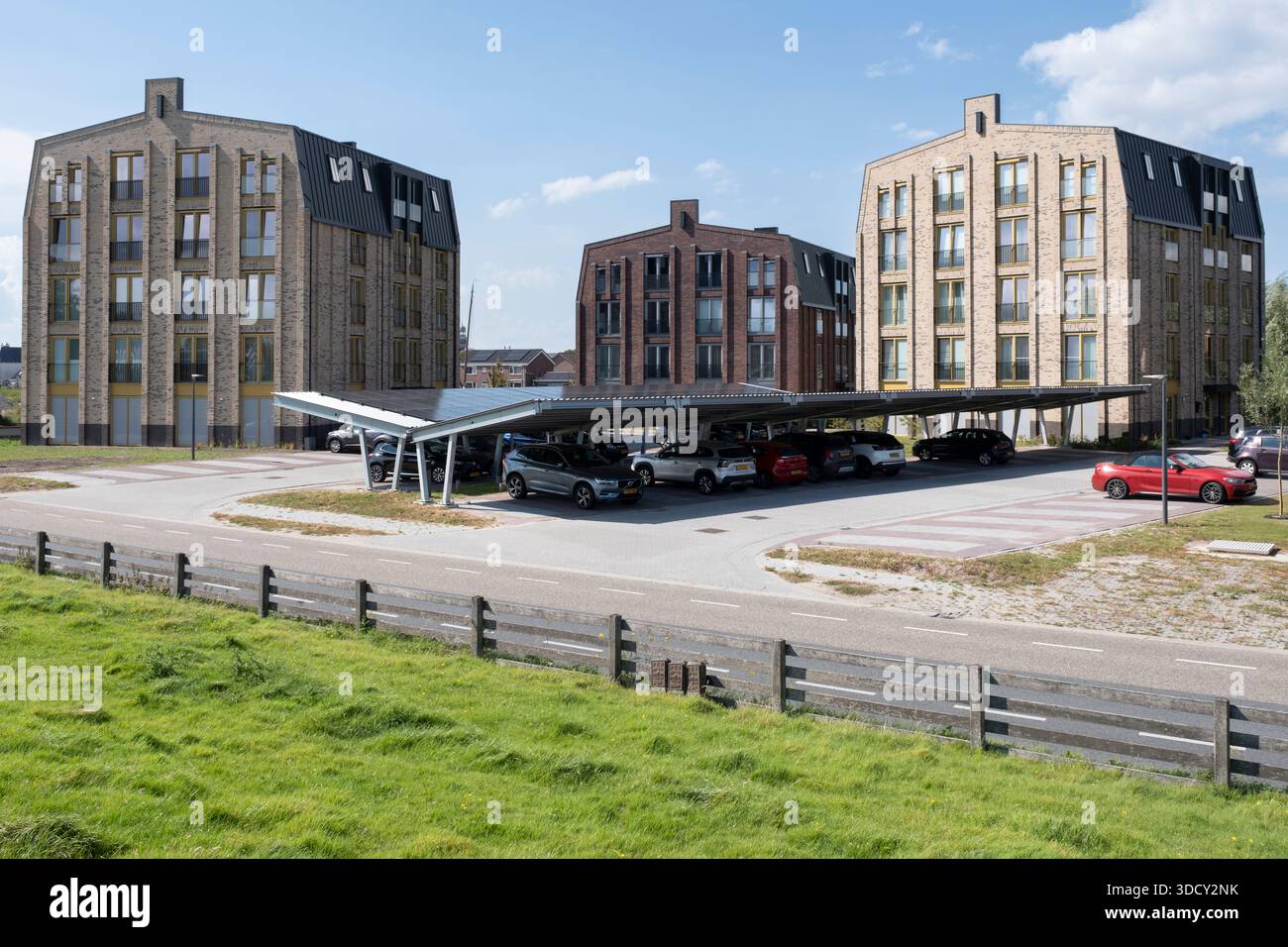 Le auto sono parcheggiate sotto una tettoia con pannelli solari in un nuovo condominio. Energia sostenibile e ombra allo stesso tempo Foto Stock