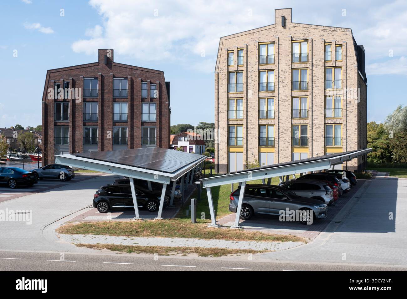 Le auto sono parcheggiate sotto una tettoia con pannelli solari in un nuovo condominio. Energia sostenibile e ombra allo stesso tempo Foto Stock