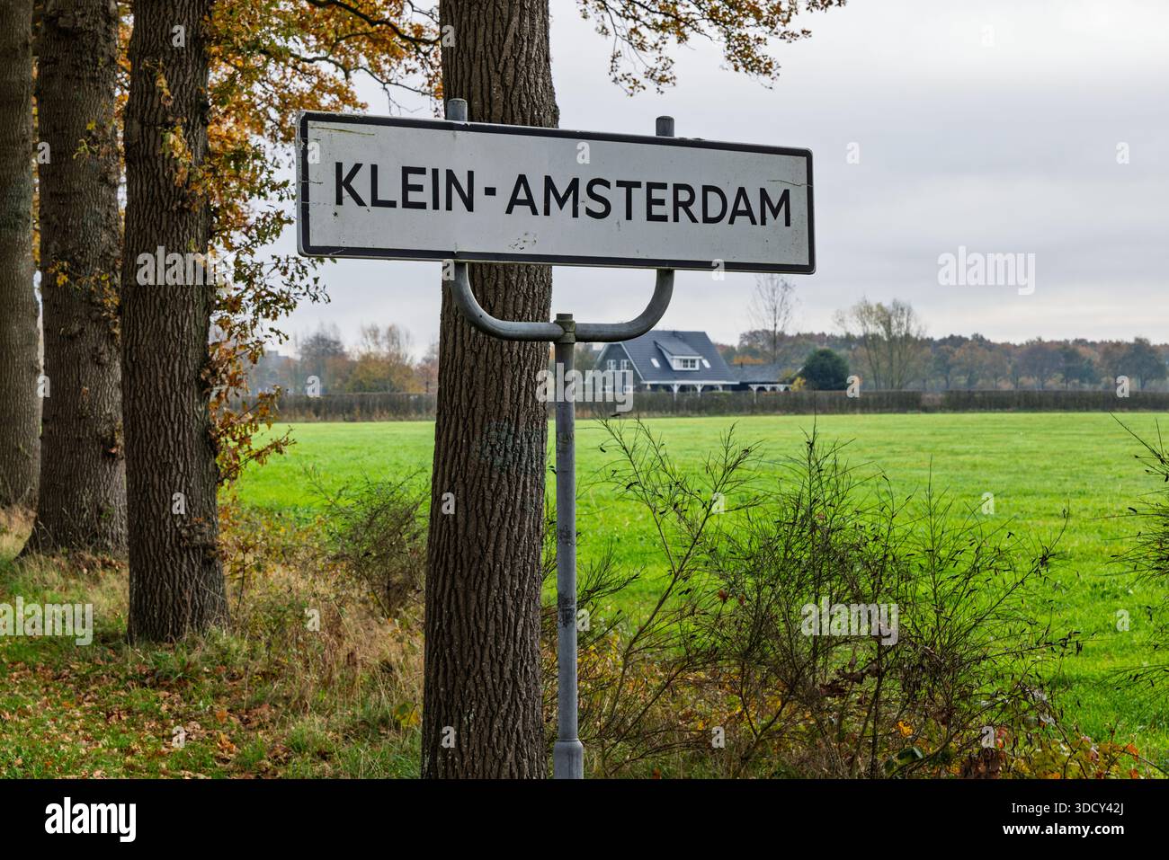 Nome bianco del piccolo borgo Klein-Amsterdam nei Paesi Bassi, immerso in un paesaggio rurale con alberi e una fattoria. Foto Stock