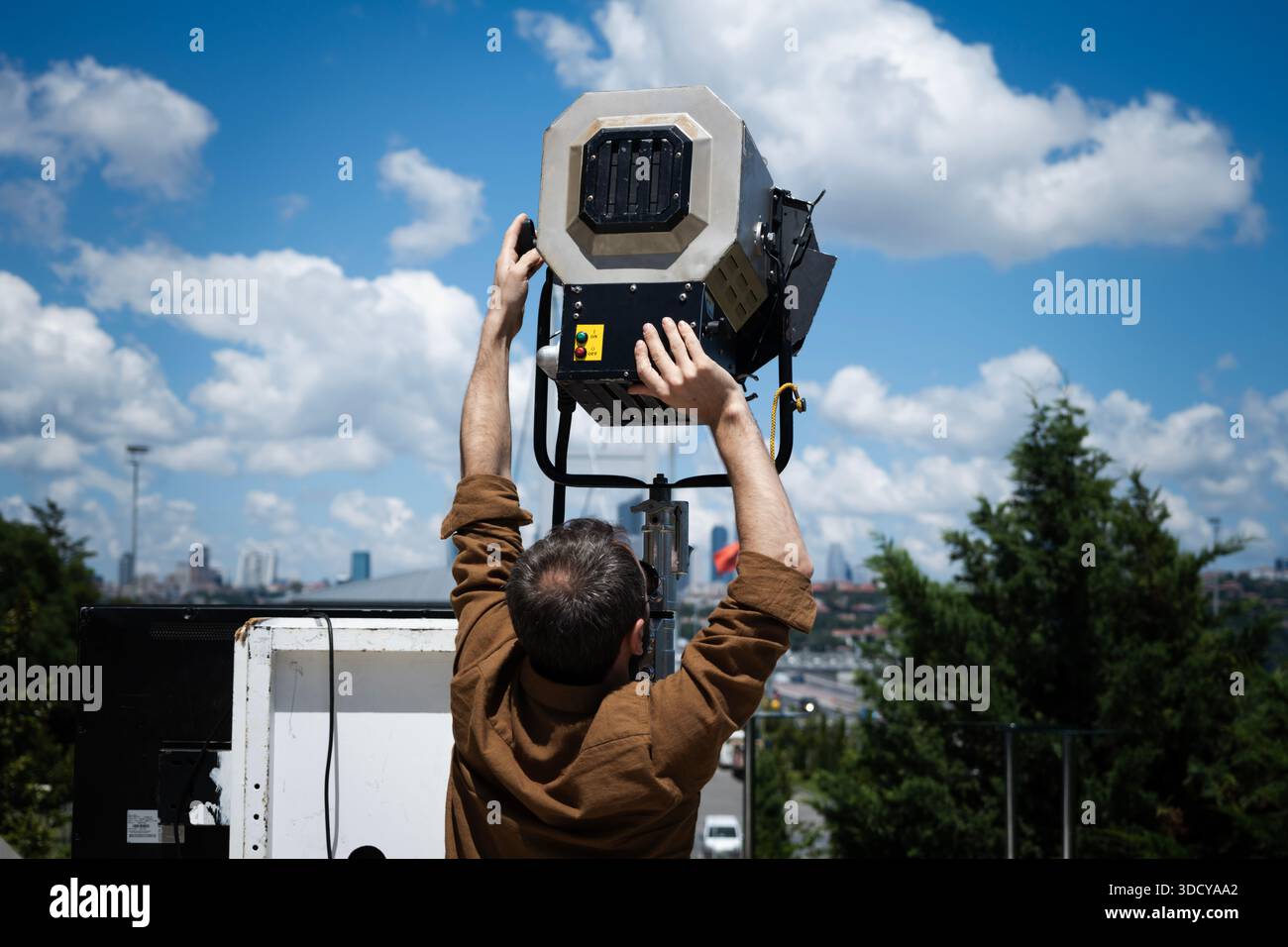 Tecnico dell'illuminazione su pellicola che regola un faretto professionale all'aperto Foto Stock