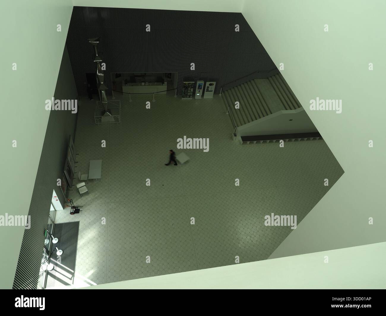 L'unica persona nel vasto spazio interno moderno - sala Filarmonica di Szczecin - Vista ad alto angolo di una singola persona che cammina attraverso una grande sala interna moderna Foto Stock