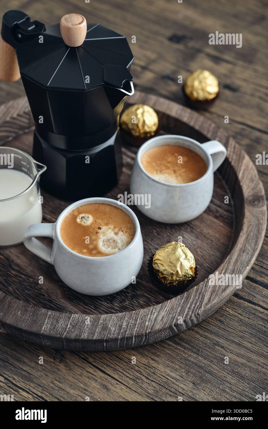 Macchina per il caffè Black moka pot con manico in legno e due tazze di caffè su vassoio in legno Foto Stock