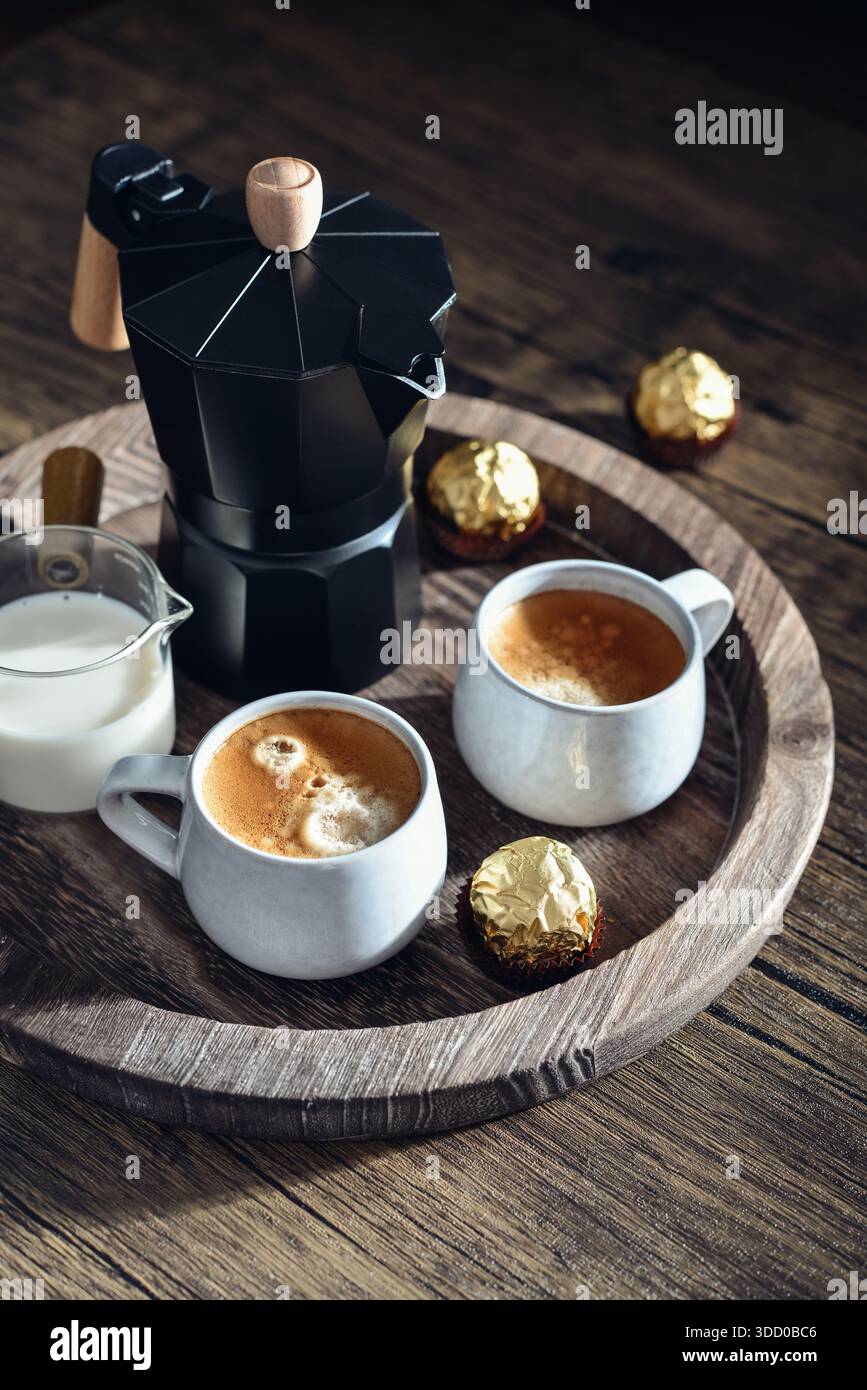 Macchina per il caffè Black moka pot con manico in legno e due tazze di caffè su vassoio in legno Foto Stock