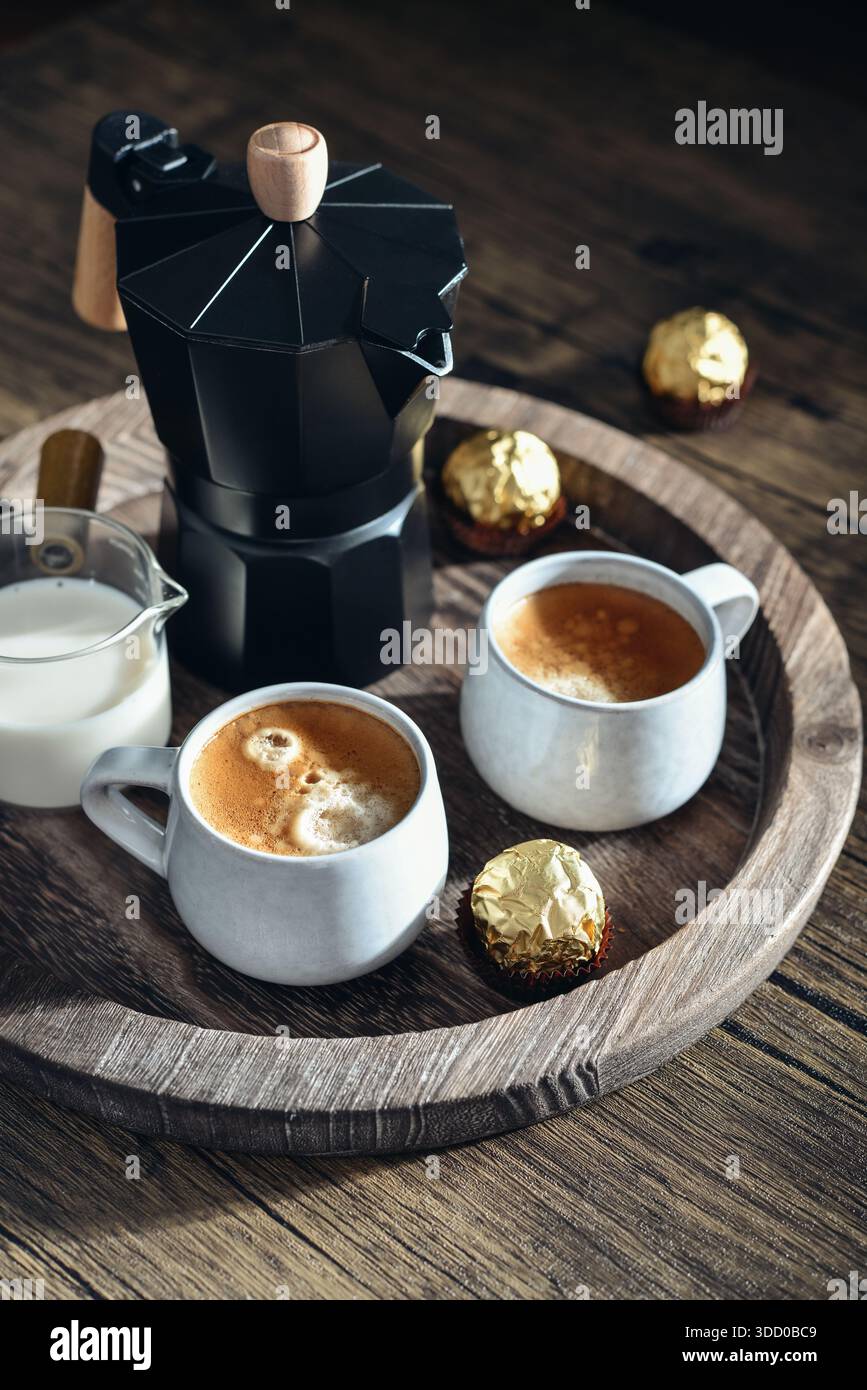 Macchina per il caffè Black moka pot con manico in legno e due tazze di caffè su vassoio in legno Foto Stock