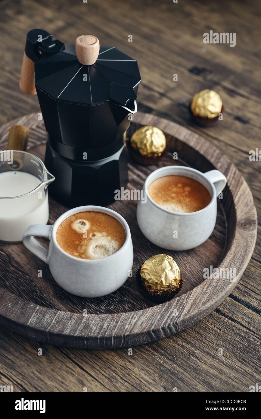 Macchina per il caffè Black moka pot con manico in legno e due tazze di caffè su vassoio in legno Foto Stock