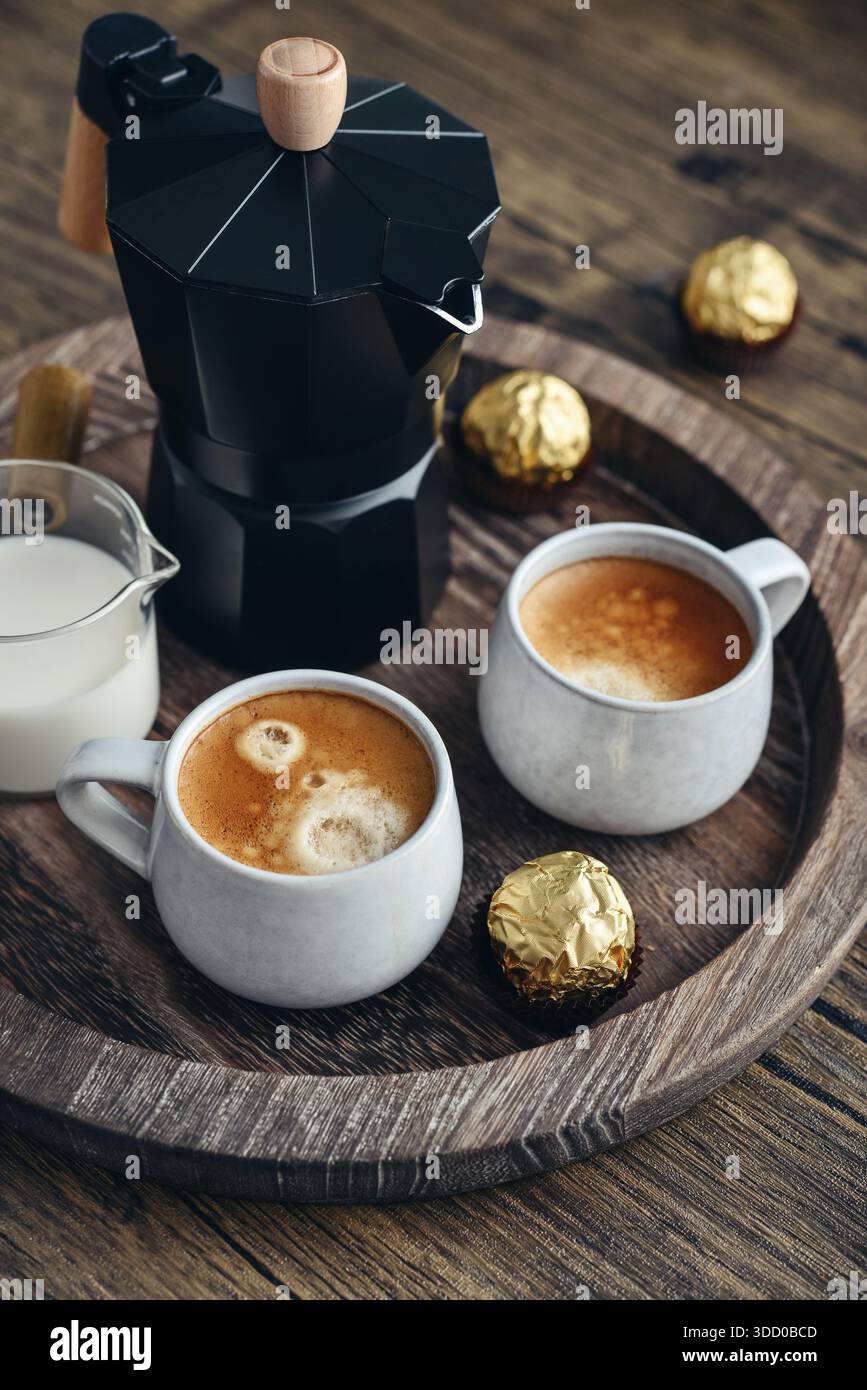 Macchina per il caffè Black moka pot con manico in legno e due tazze di caffè su vassoio in legno Foto Stock