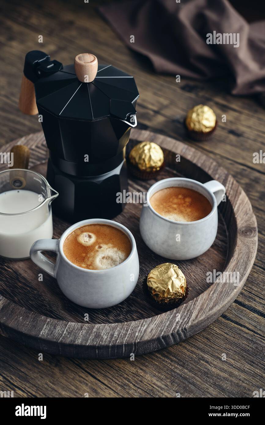 Macchina per il caffè Black moka pot con manico in legno e due tazze di caffè su vassoio in legno Foto Stock