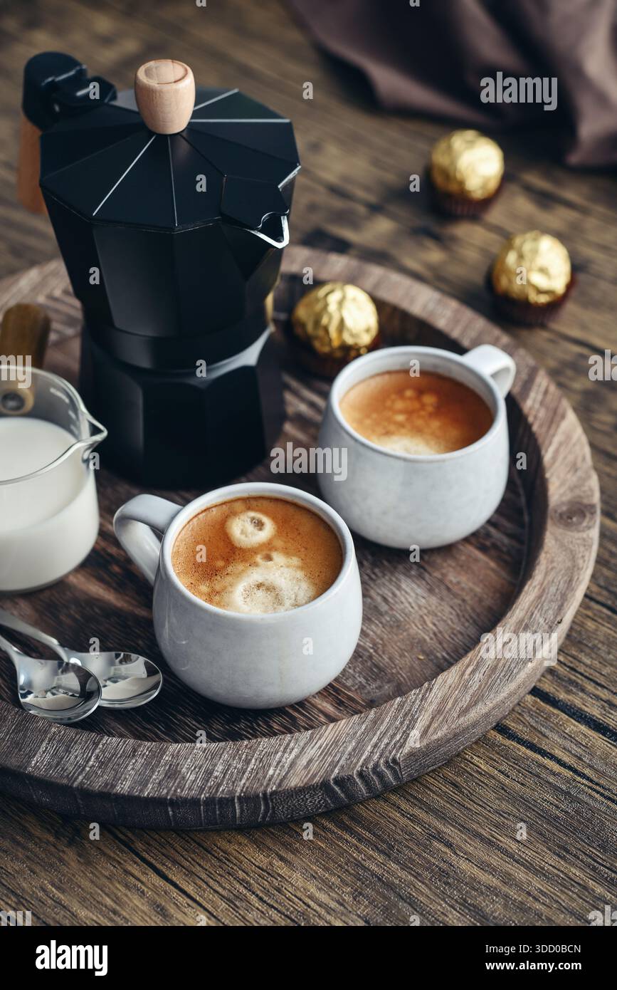 Macchina per il caffè Black moka pot con manico in legno e due tazze di caffè su vassoio in legno Foto Stock
