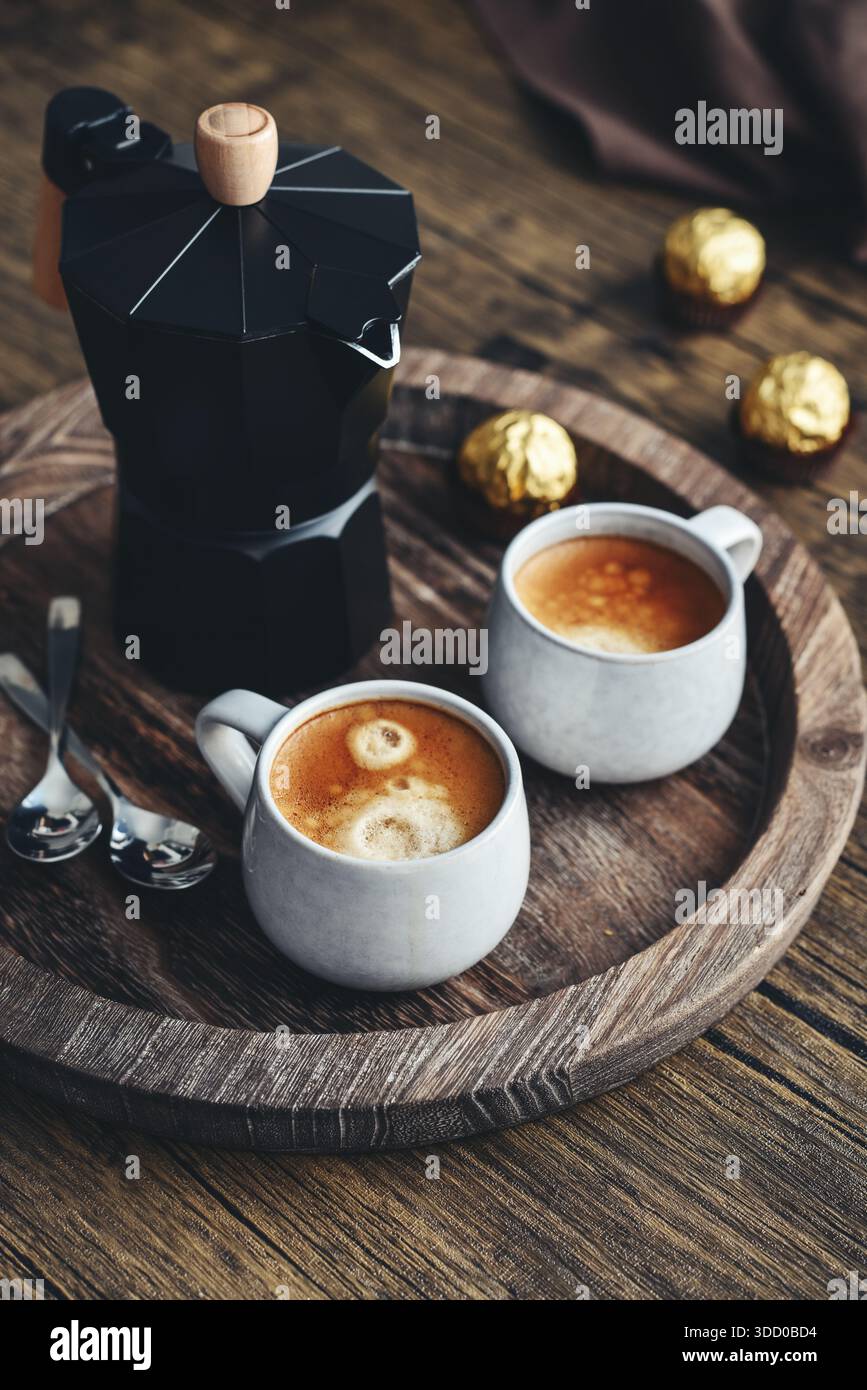 Macchina per il caffè Black moka pot con manico in legno e due tazze di caffè su vassoio in legno Foto Stock
