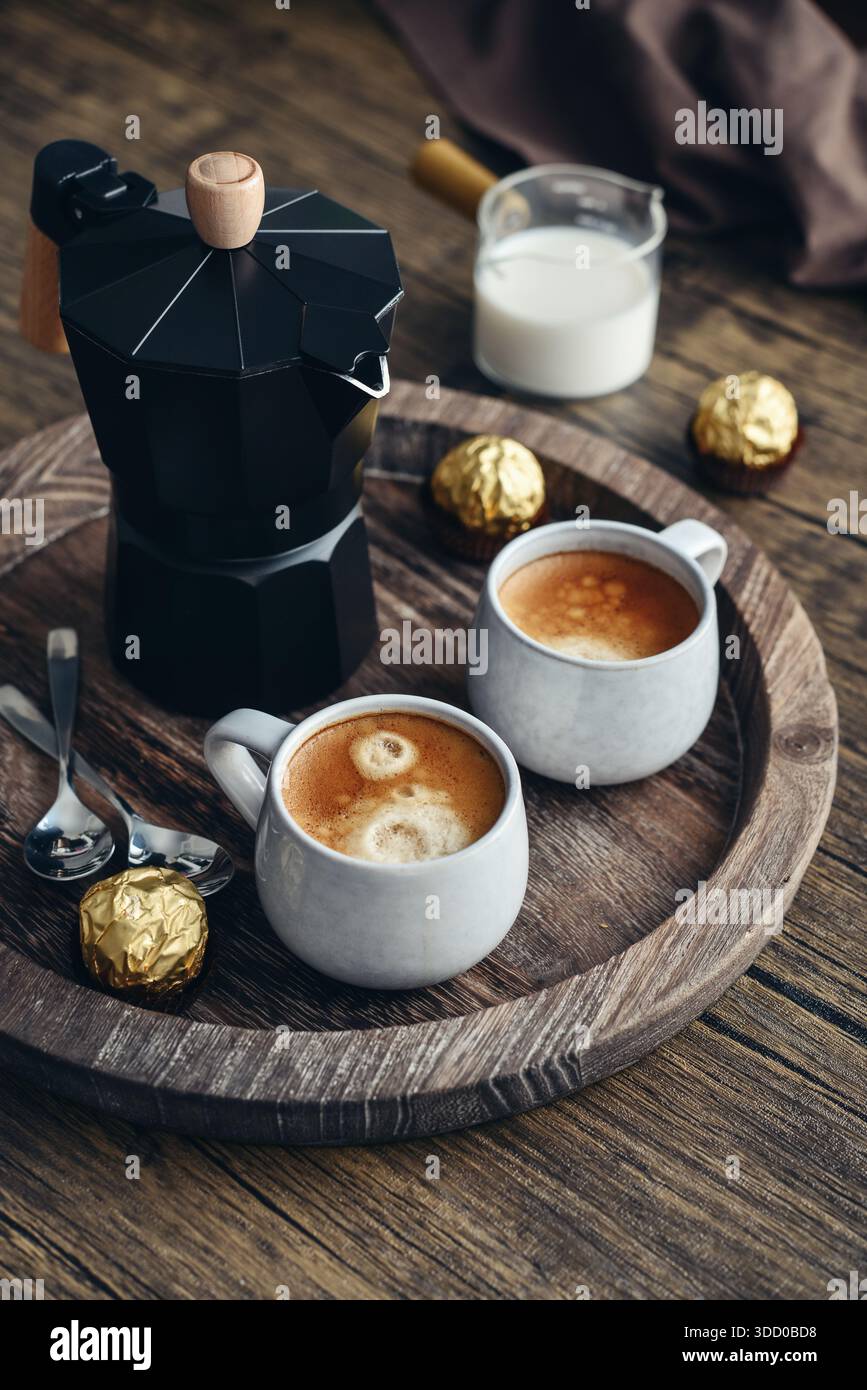 Macchina per il caffè Black moka pot con manico in legno e due tazze di caffè su vassoio in legno Foto Stock