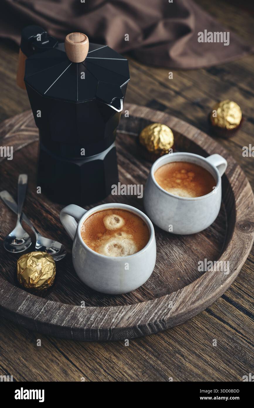 Macchina per il caffè Black moka pot con manico in legno e due tazze di caffè su vassoio in legno Foto Stock