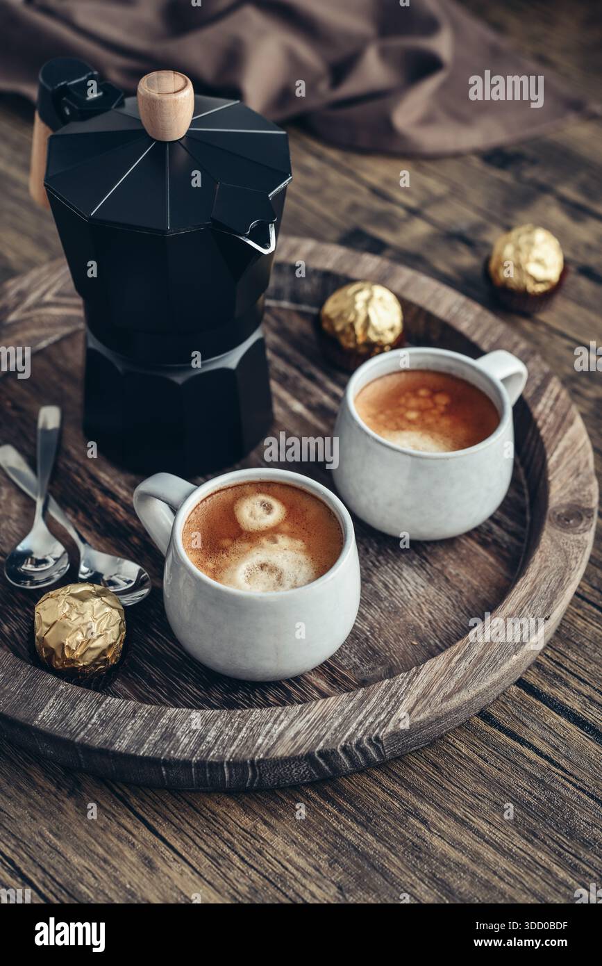 Macchina per il caffè Black moka pot con manico in legno e due tazze di caffè su vassoio in legno Foto Stock